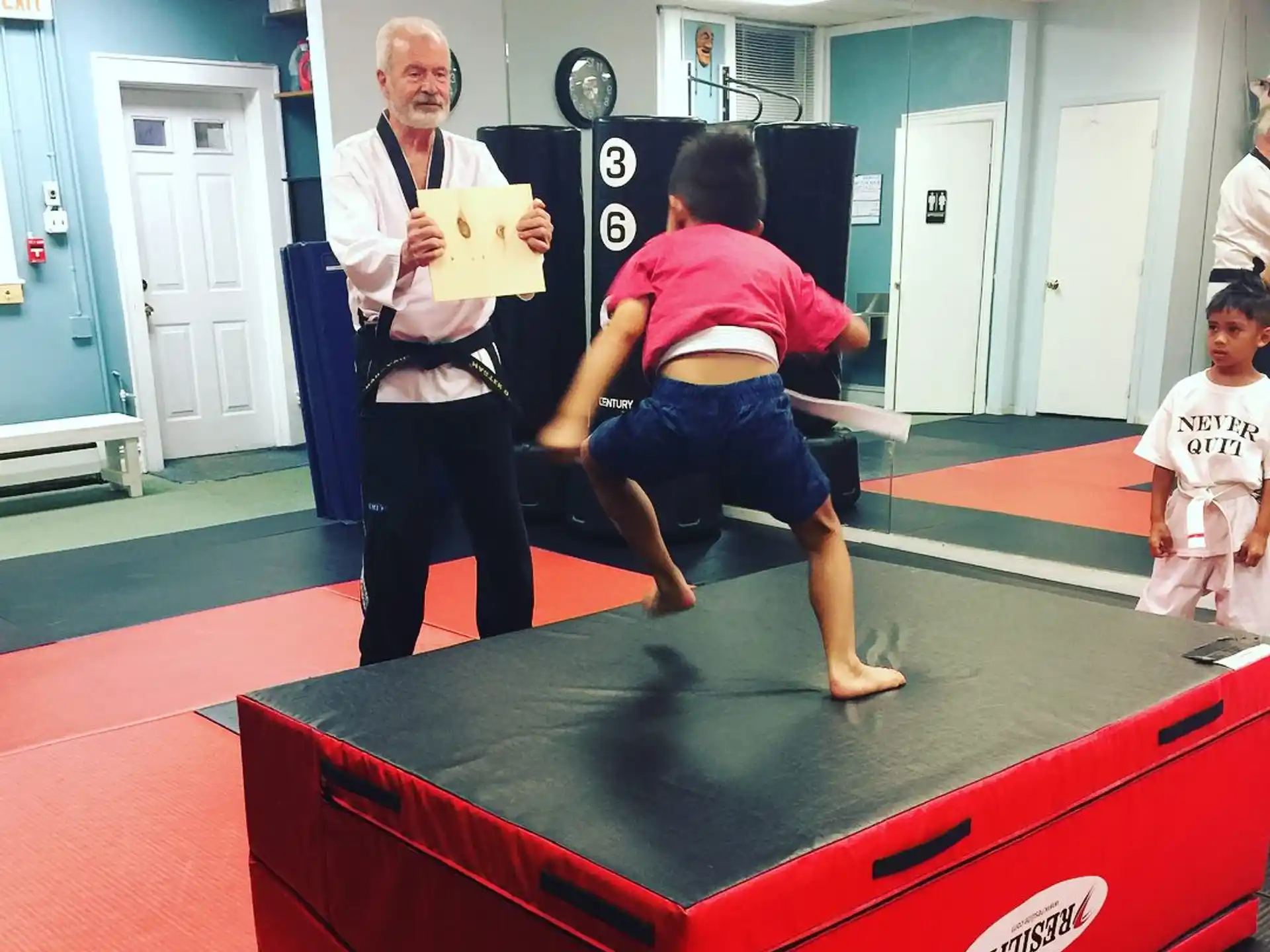 a person standing on a red mat with a person sitting on it