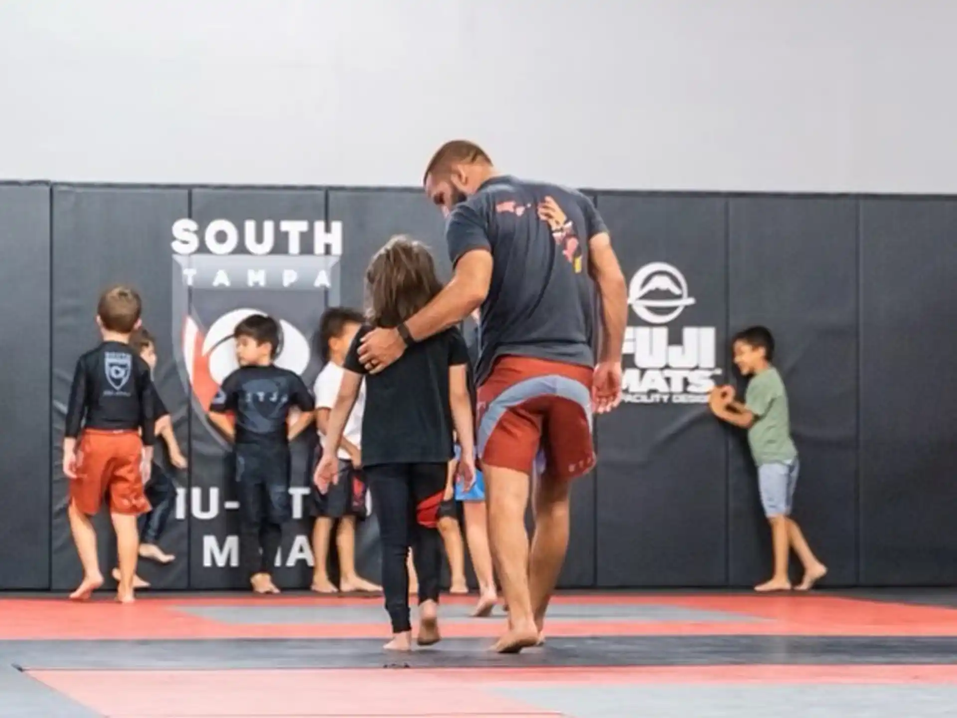 a man and a woman kissing on a mat with a group of children