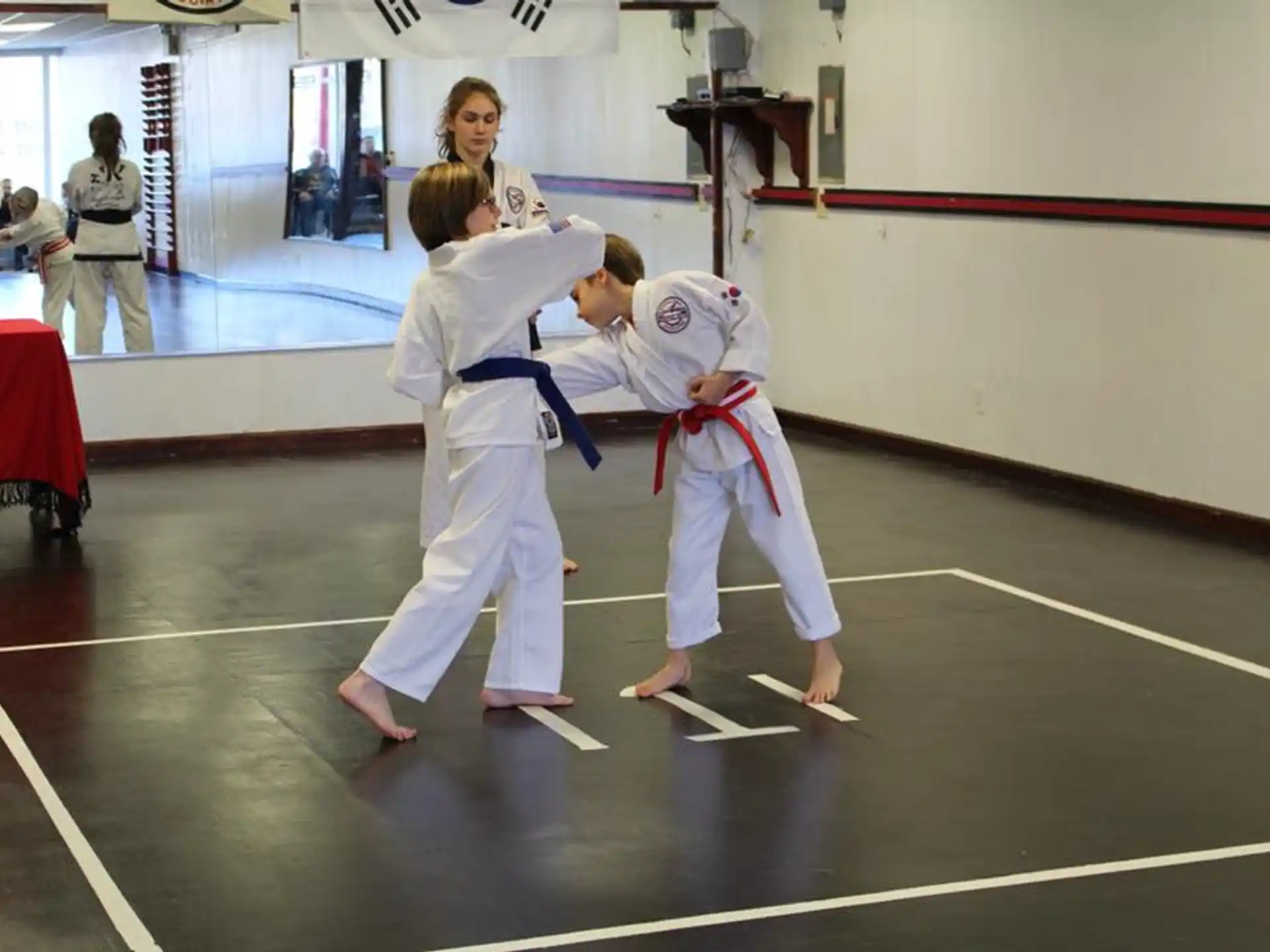 a man and a woman in karate uniforms in a room with other people