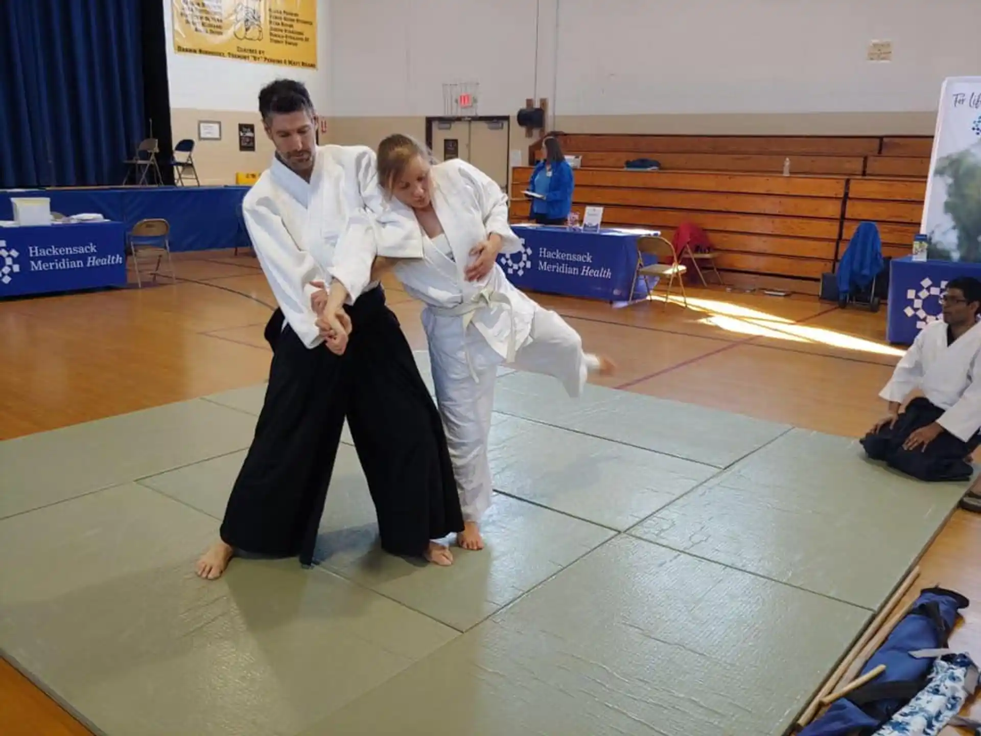 a man and a woman in karate uniforms in a room with other people