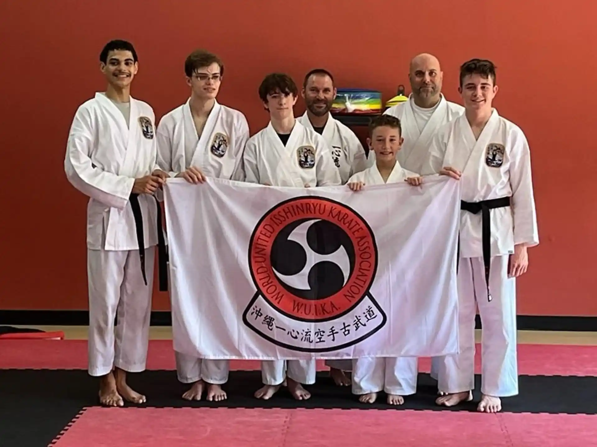 a group of men in white karate uniforms holding a flag