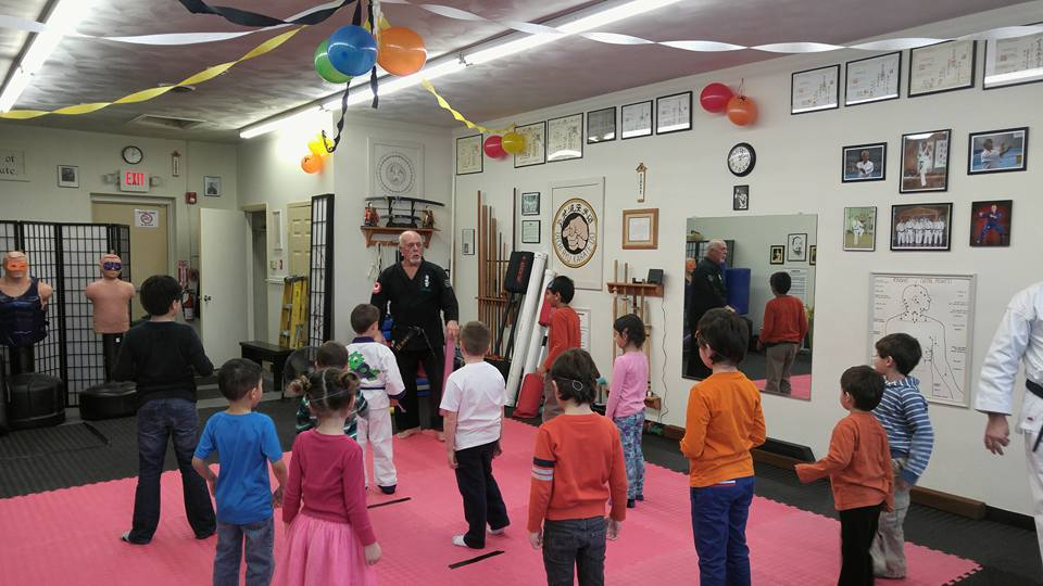 a group of children in a room with balloons and a person standing