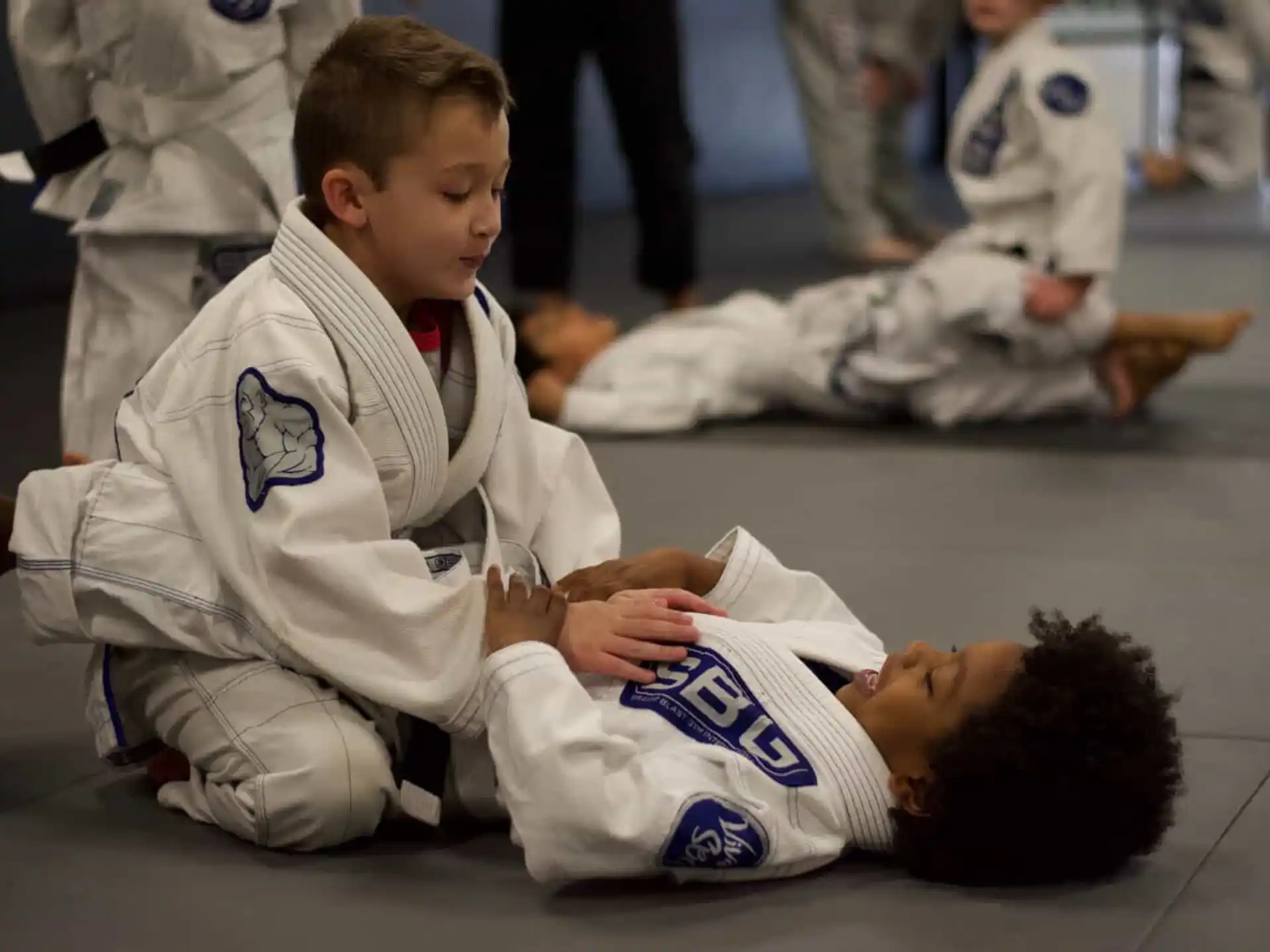 a person in a karate uniform kneeling down next to a person in a white uniform