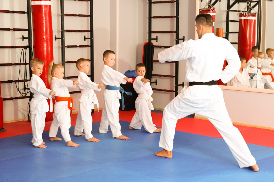 a man in white karate uniform with a group of boys in white karate uniforms