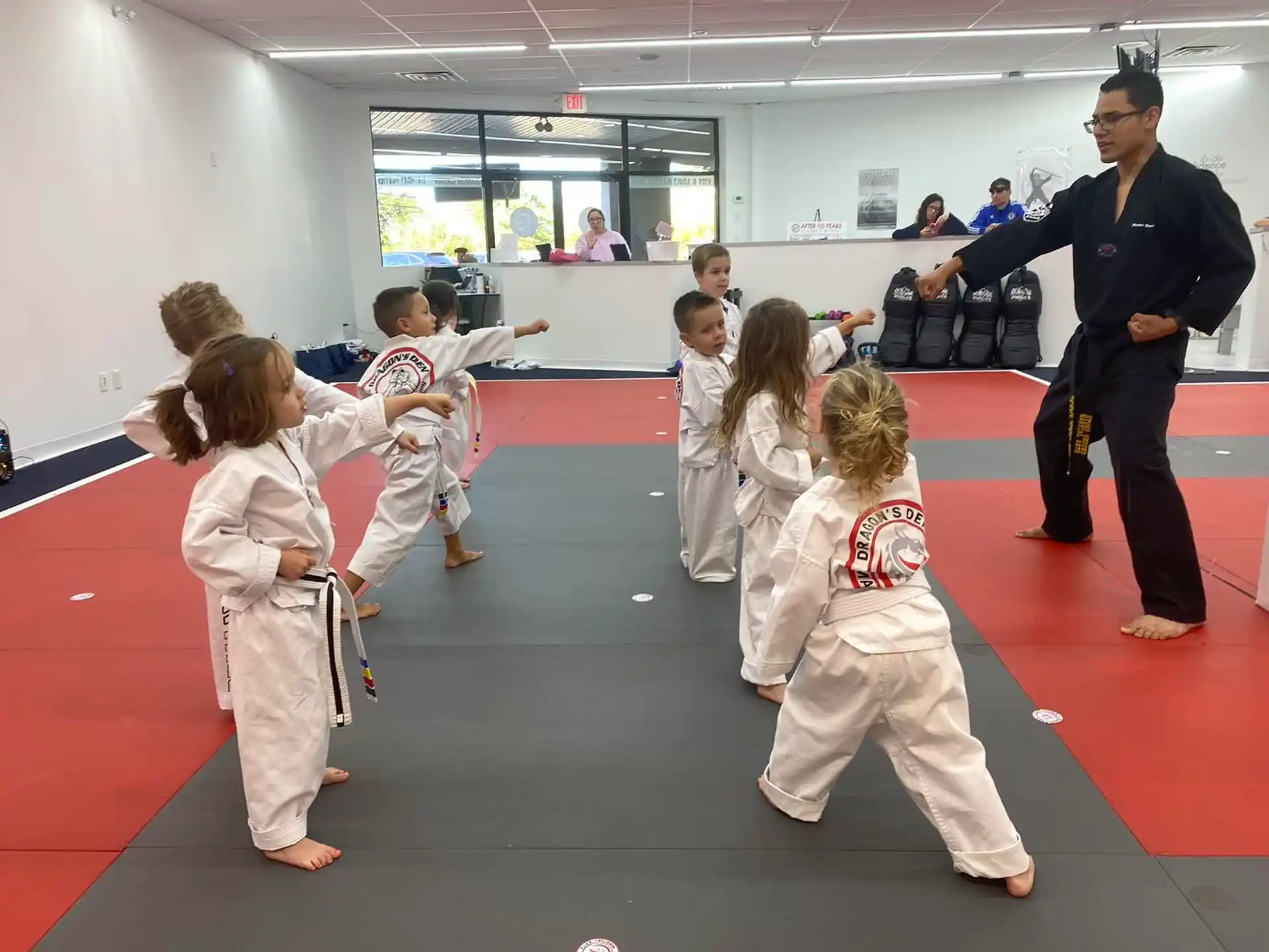 a person standing in front of a group of children in karate uniforms