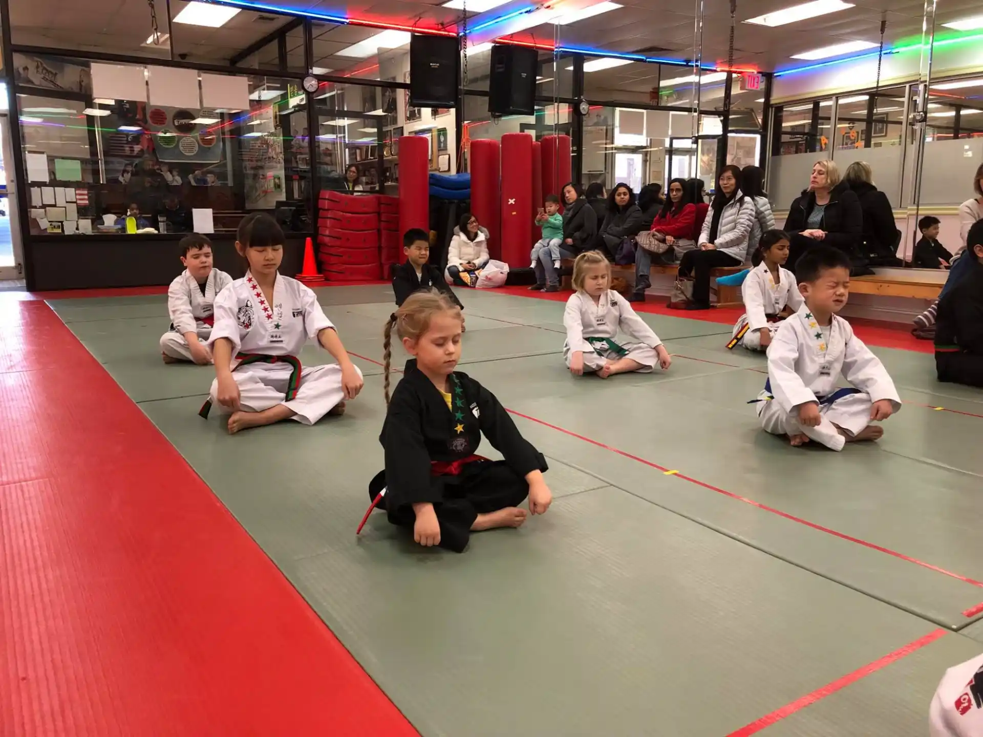 a group of children sitting on the floor in a gym