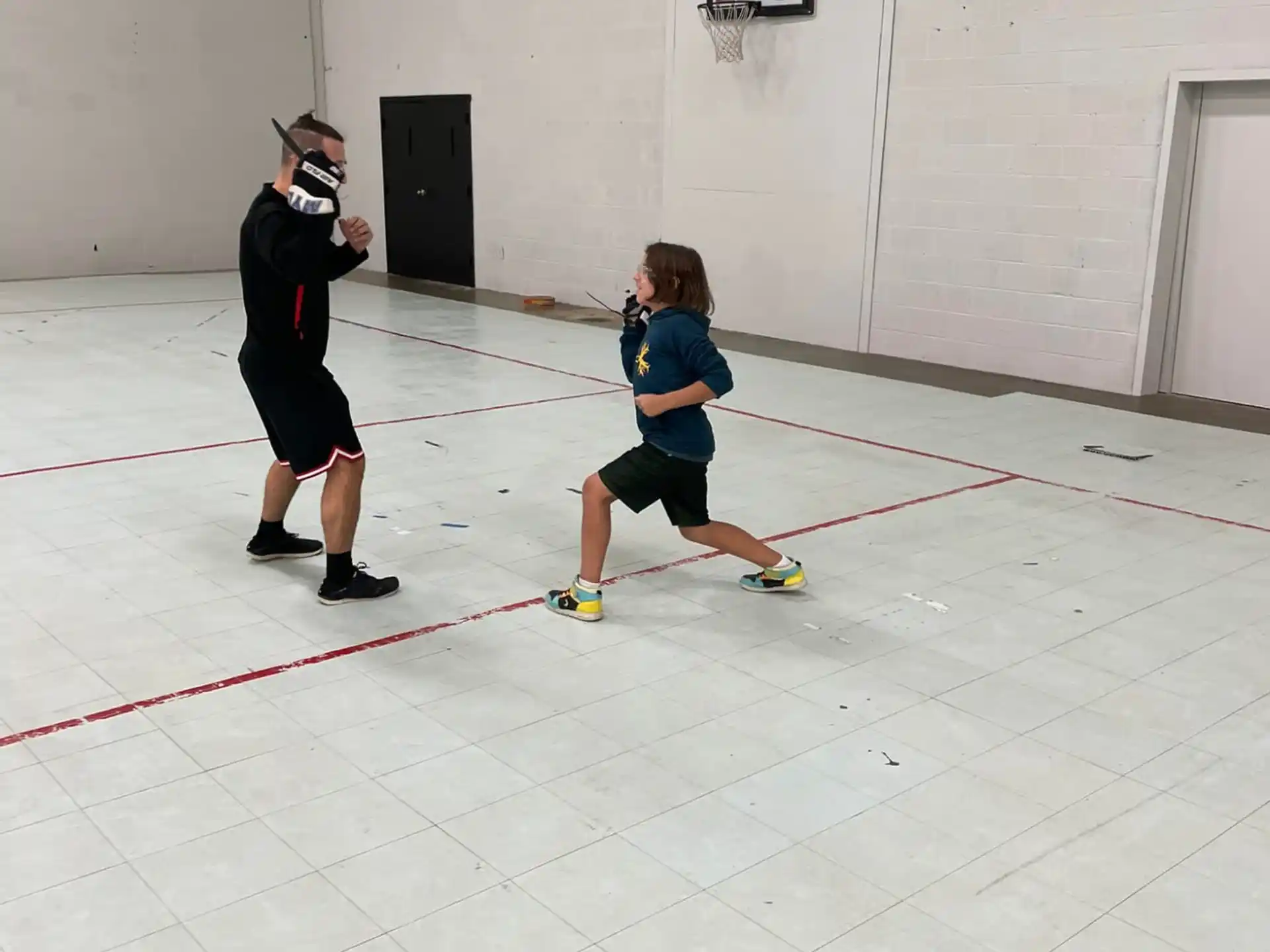 a boy playing hockey with a person watching