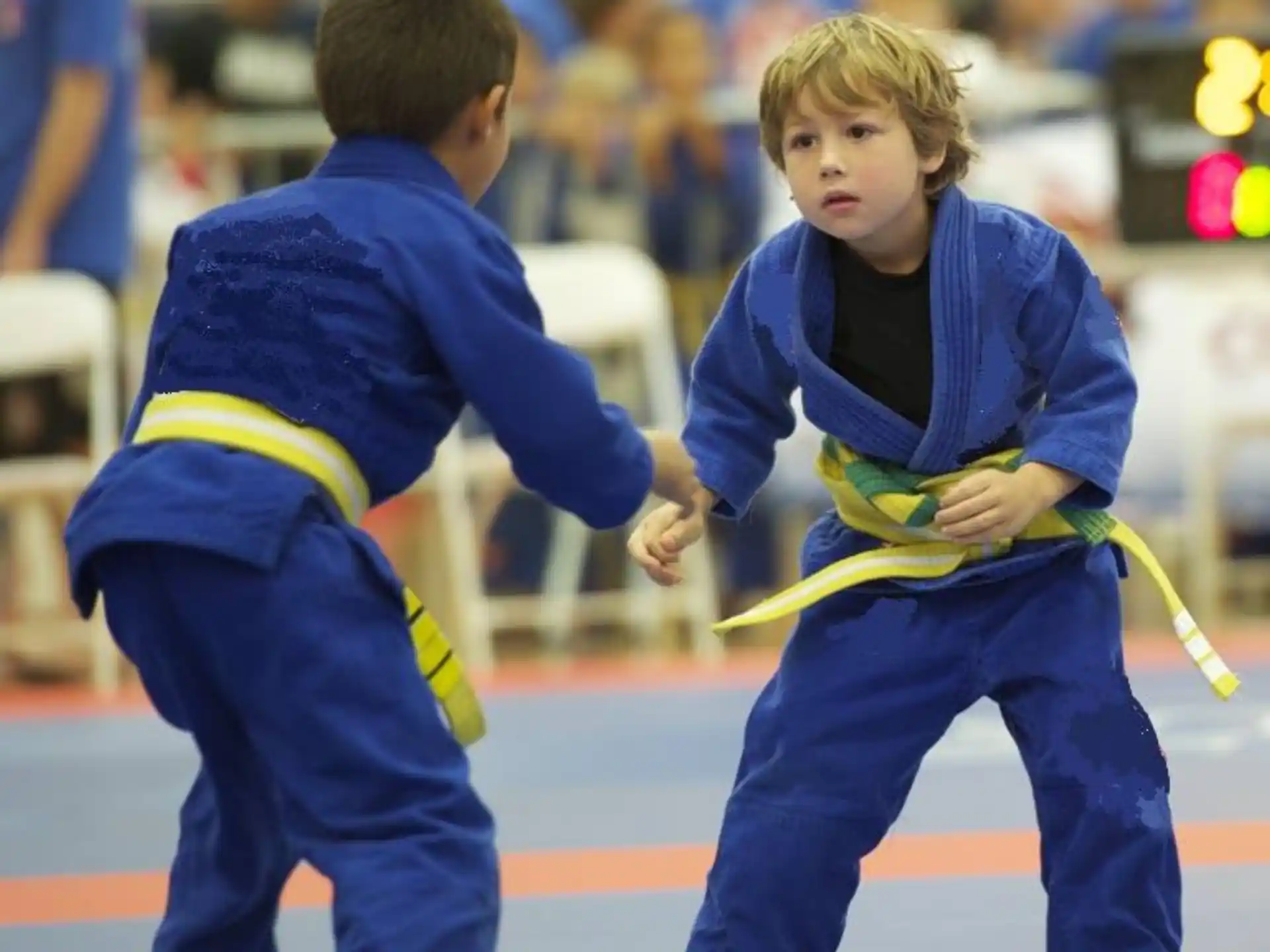a couple of kids in blue karate uniforms holding yellow sticks
