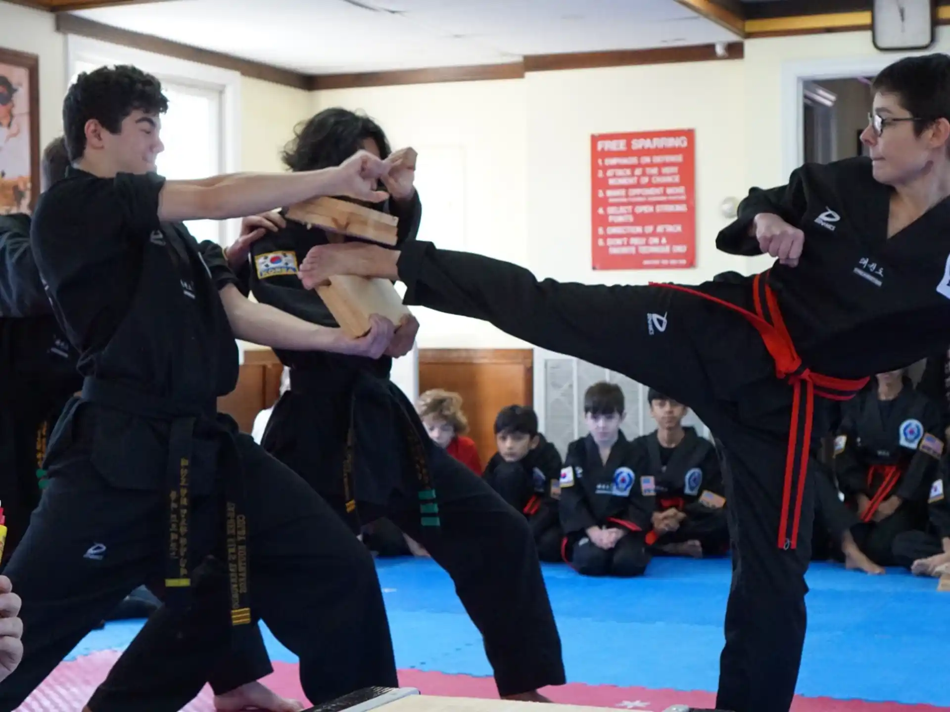 a group of men in martial arts uniforms in a room with people