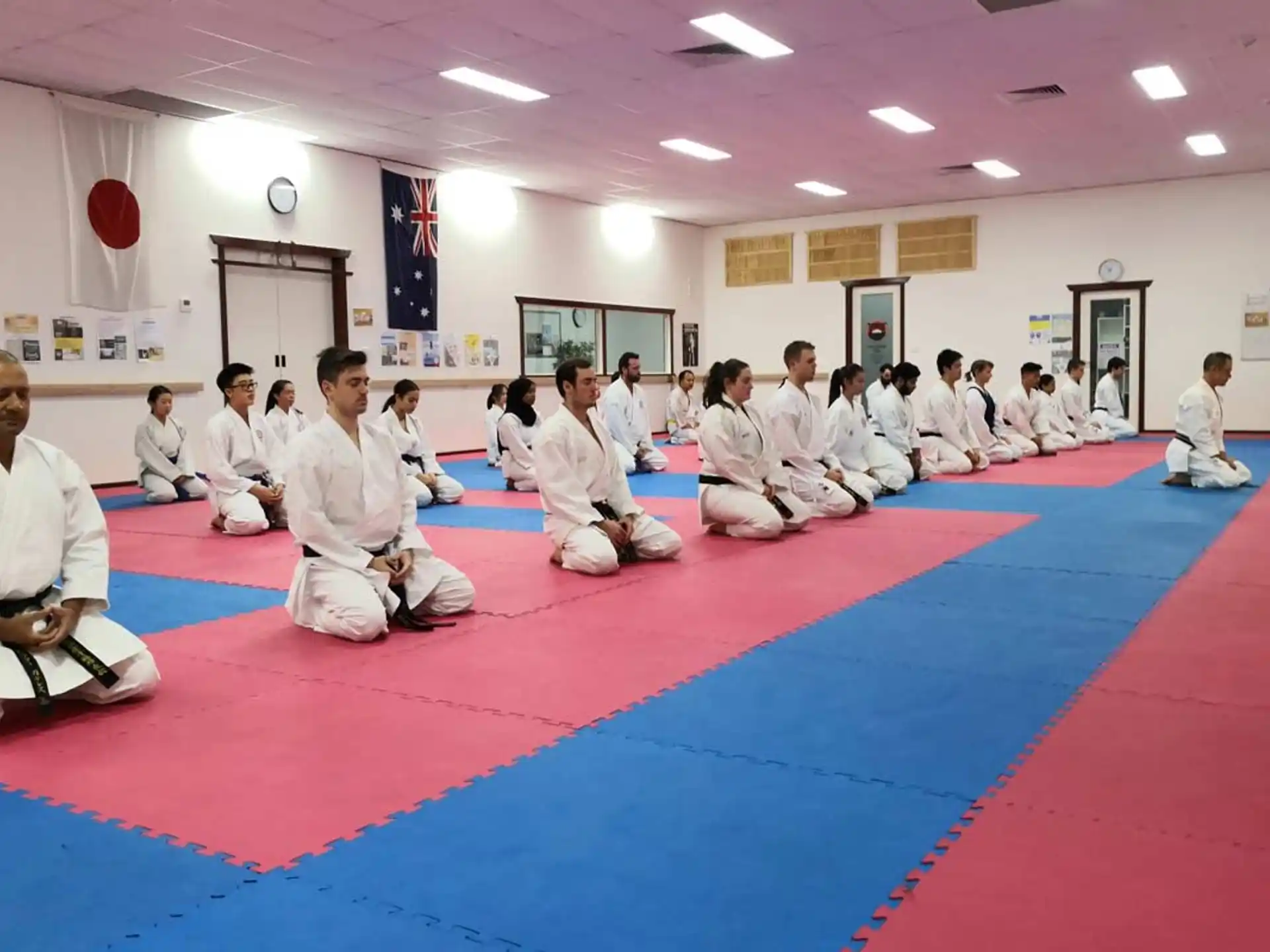 a group of people in white uniforms sitting on a mat