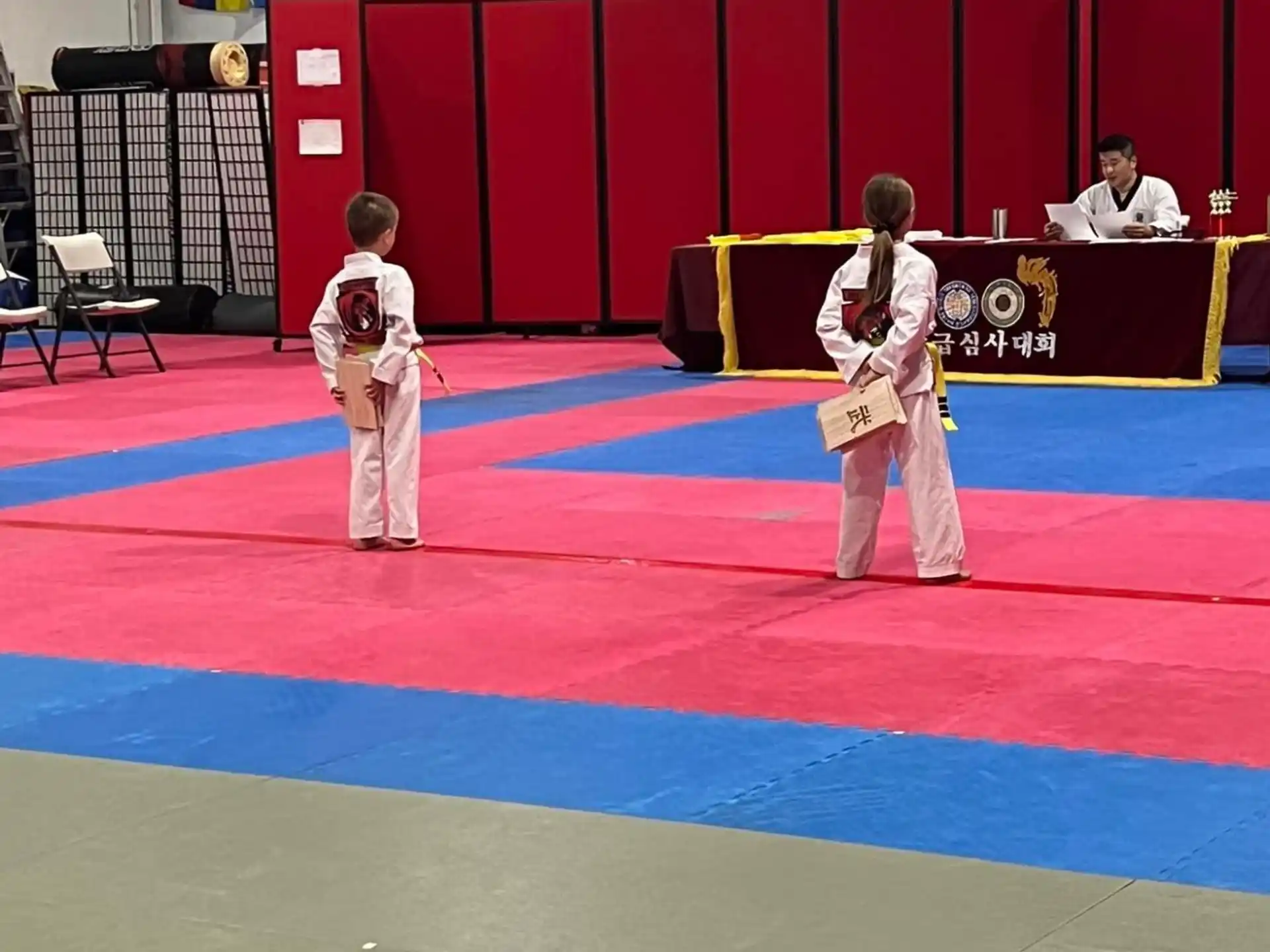 a person and a boy in karate uniforms on a mat