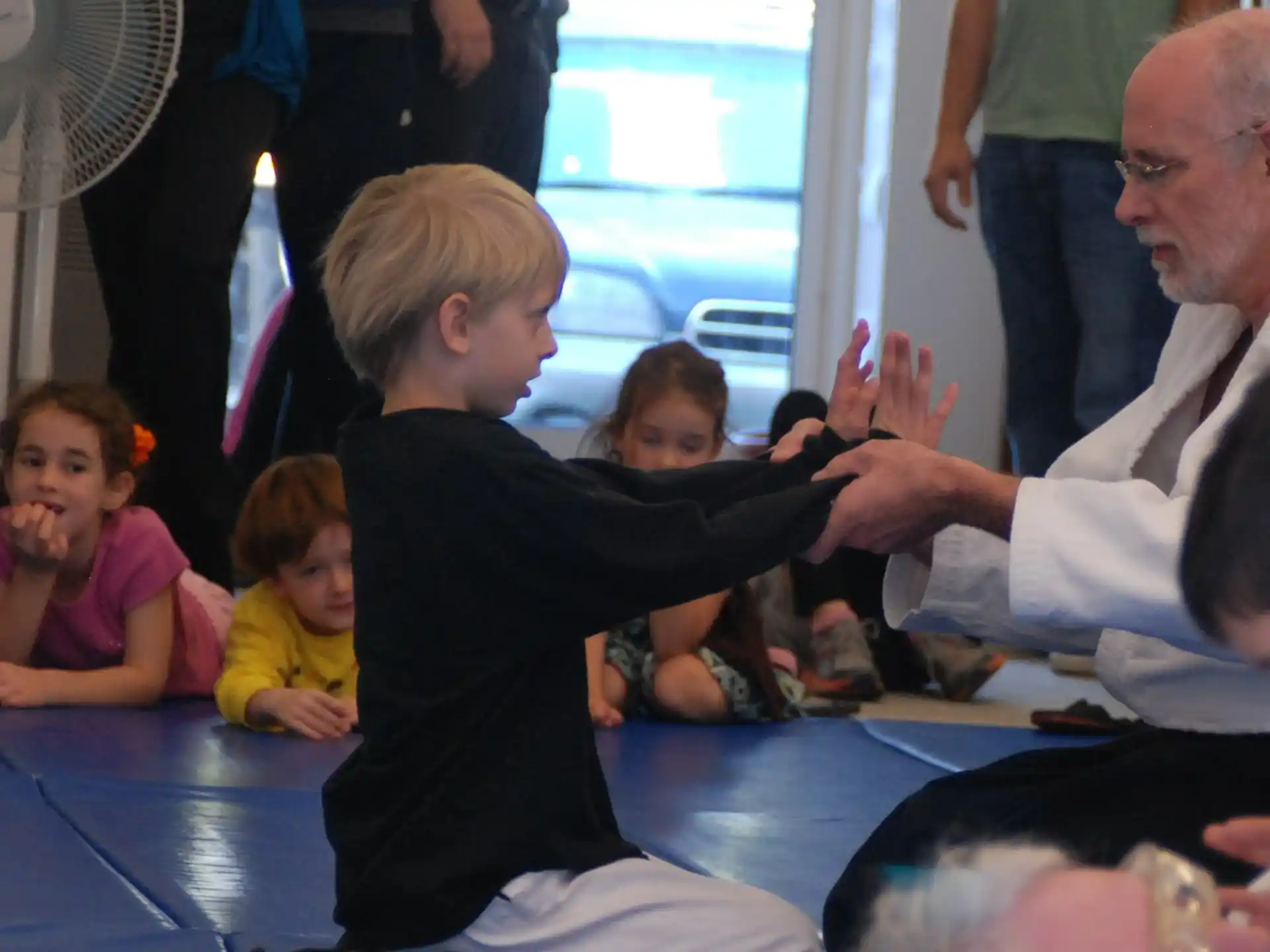 a man and a boy sitting on the floor with a man and a woman standing behind him