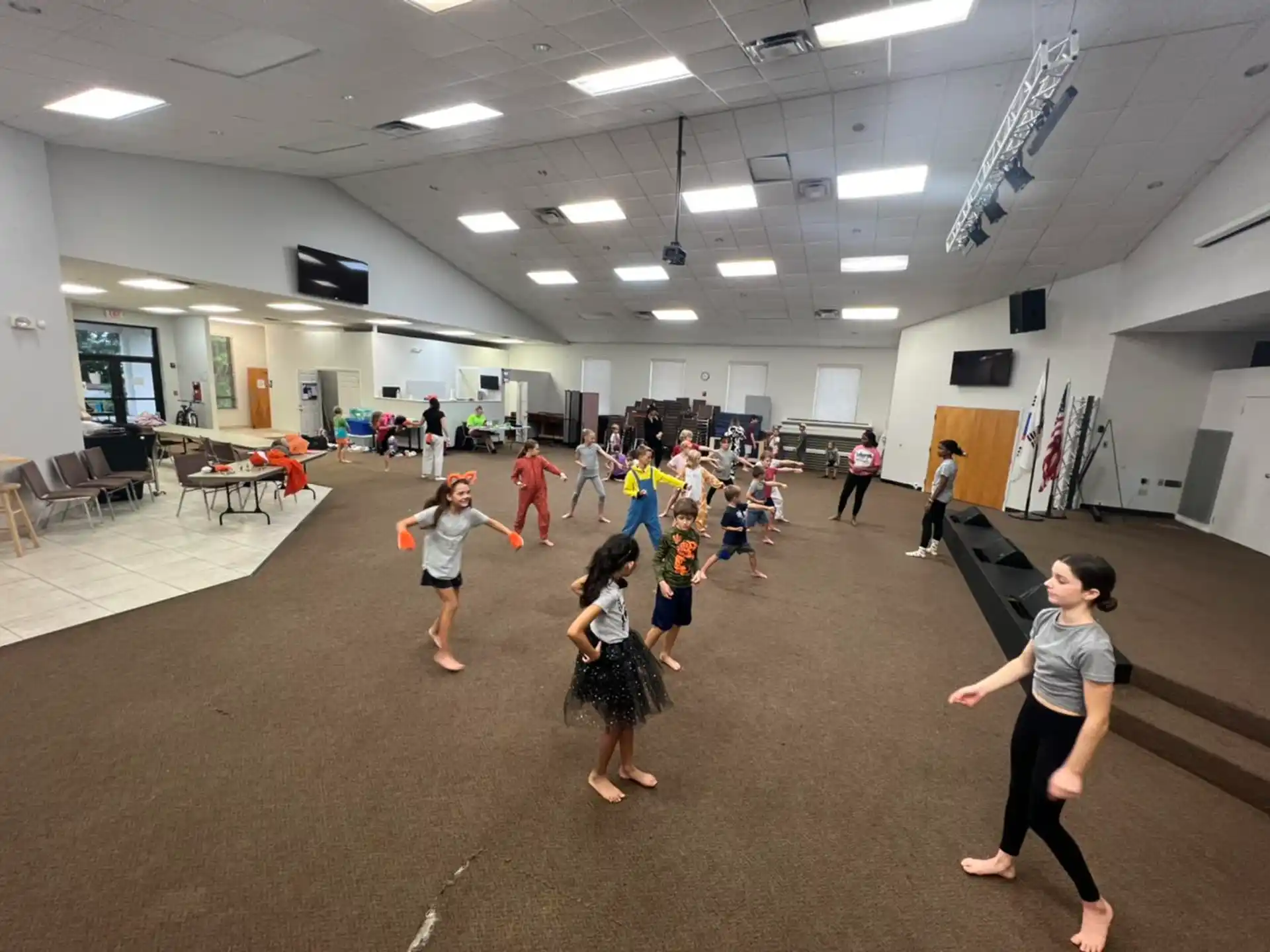 a group of people dancing in a room with tables and chairs