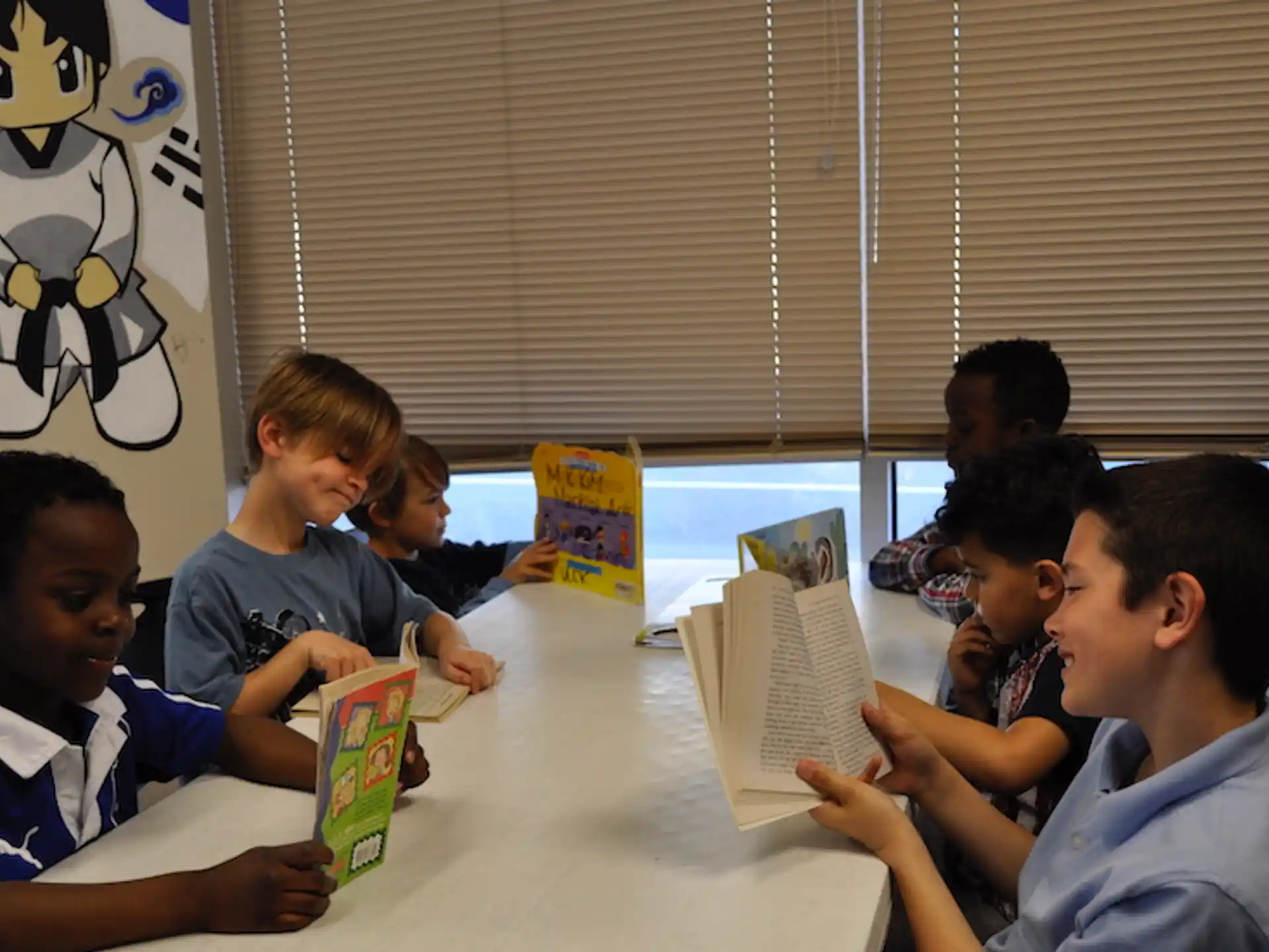 a group of children sitting at a table reading books