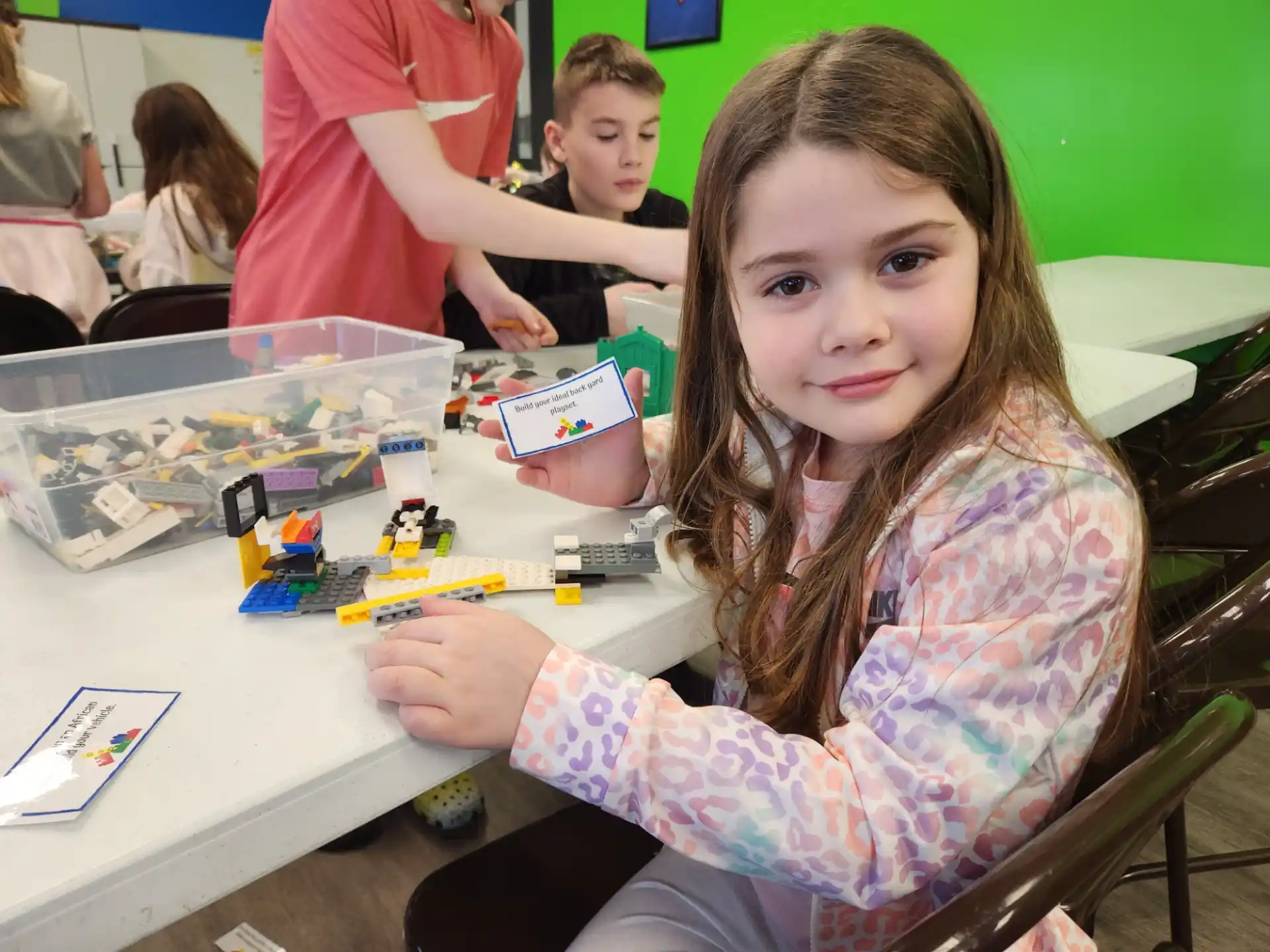 a girl sitting at a table with a toy