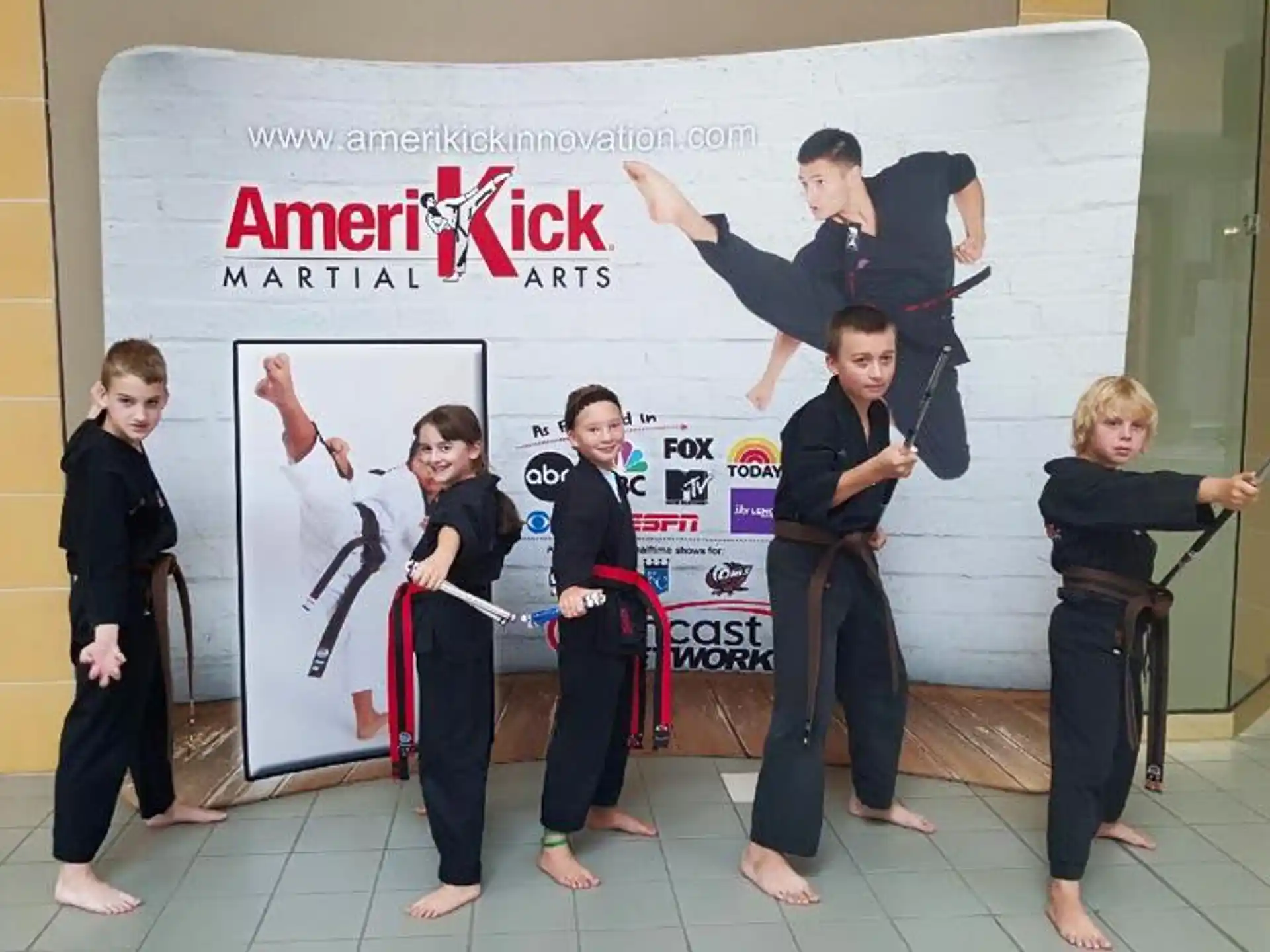 a group of children in black karate uniforms holding their hands up