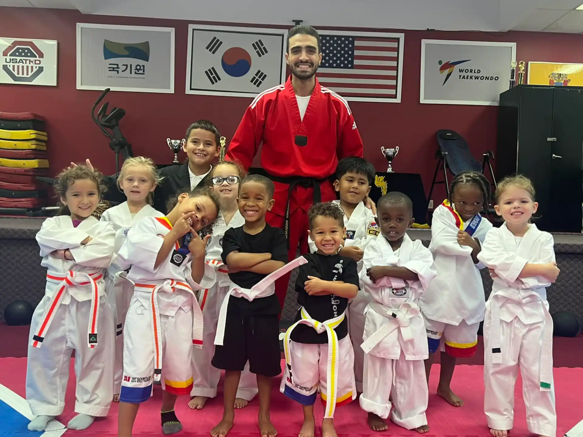a person standing behind a group of kids in karate uniforms
