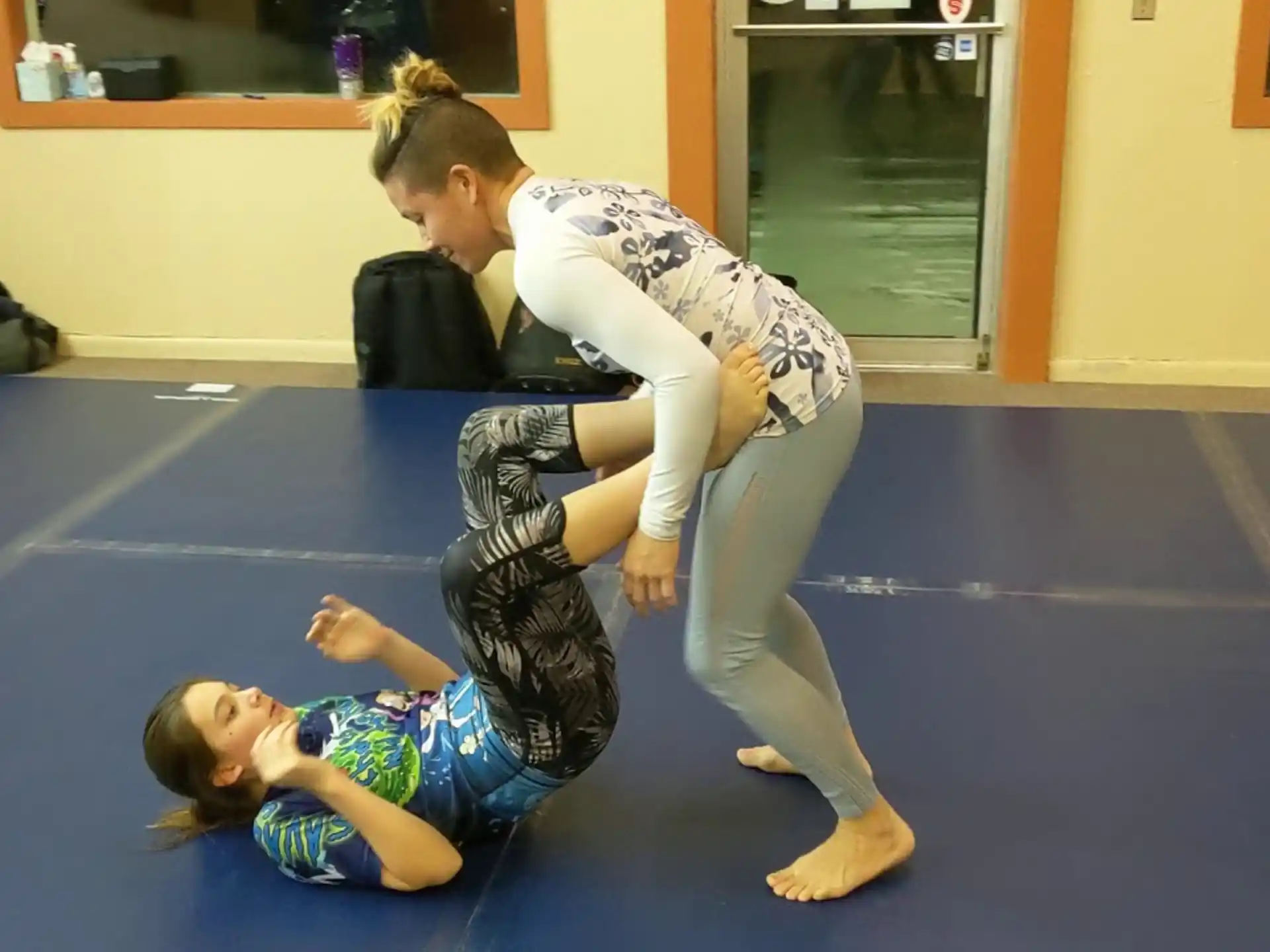 a woman doing a plank on a mat with another woman standing behind her