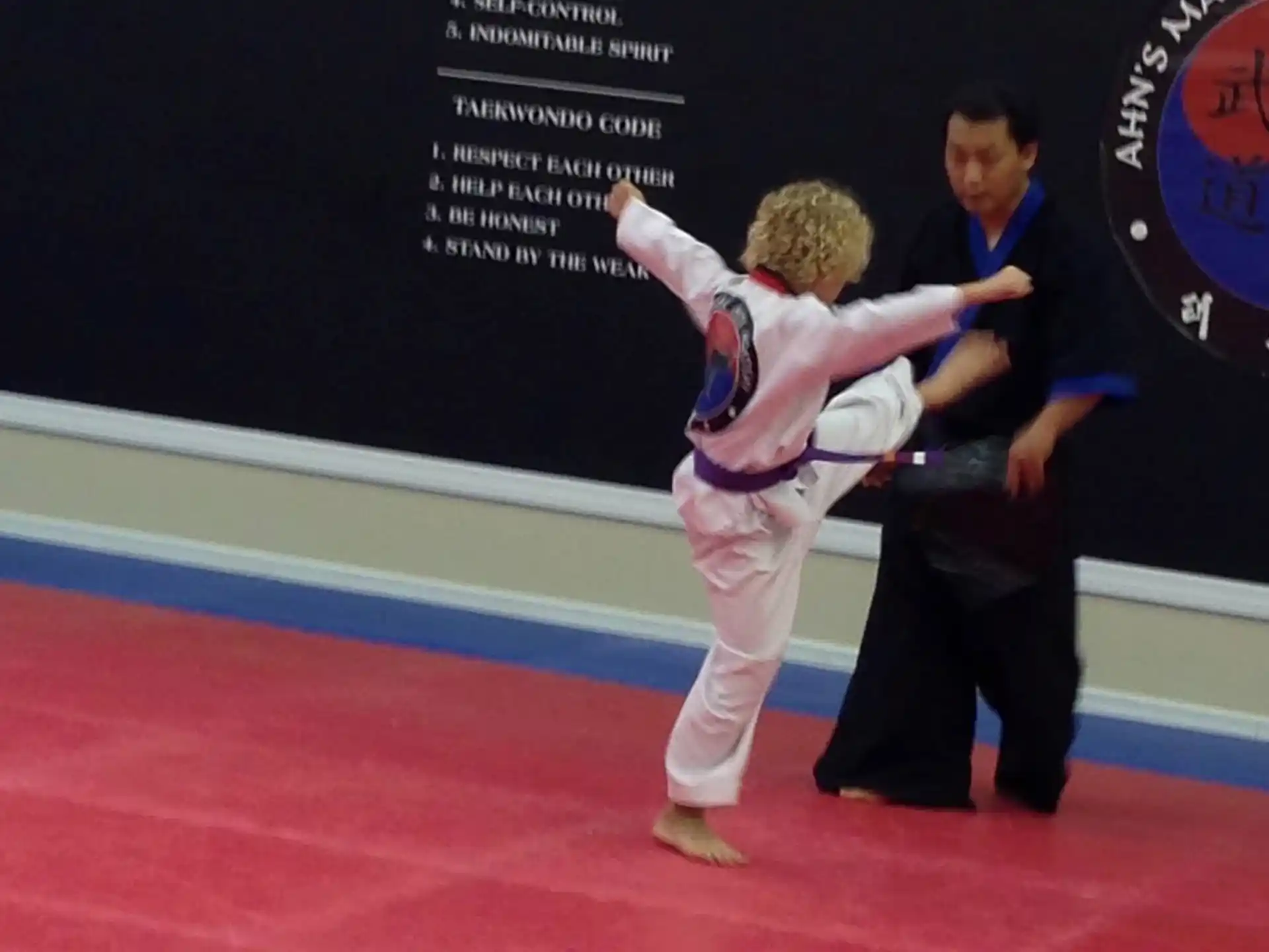a person in a karate uniform kicking another man in the face