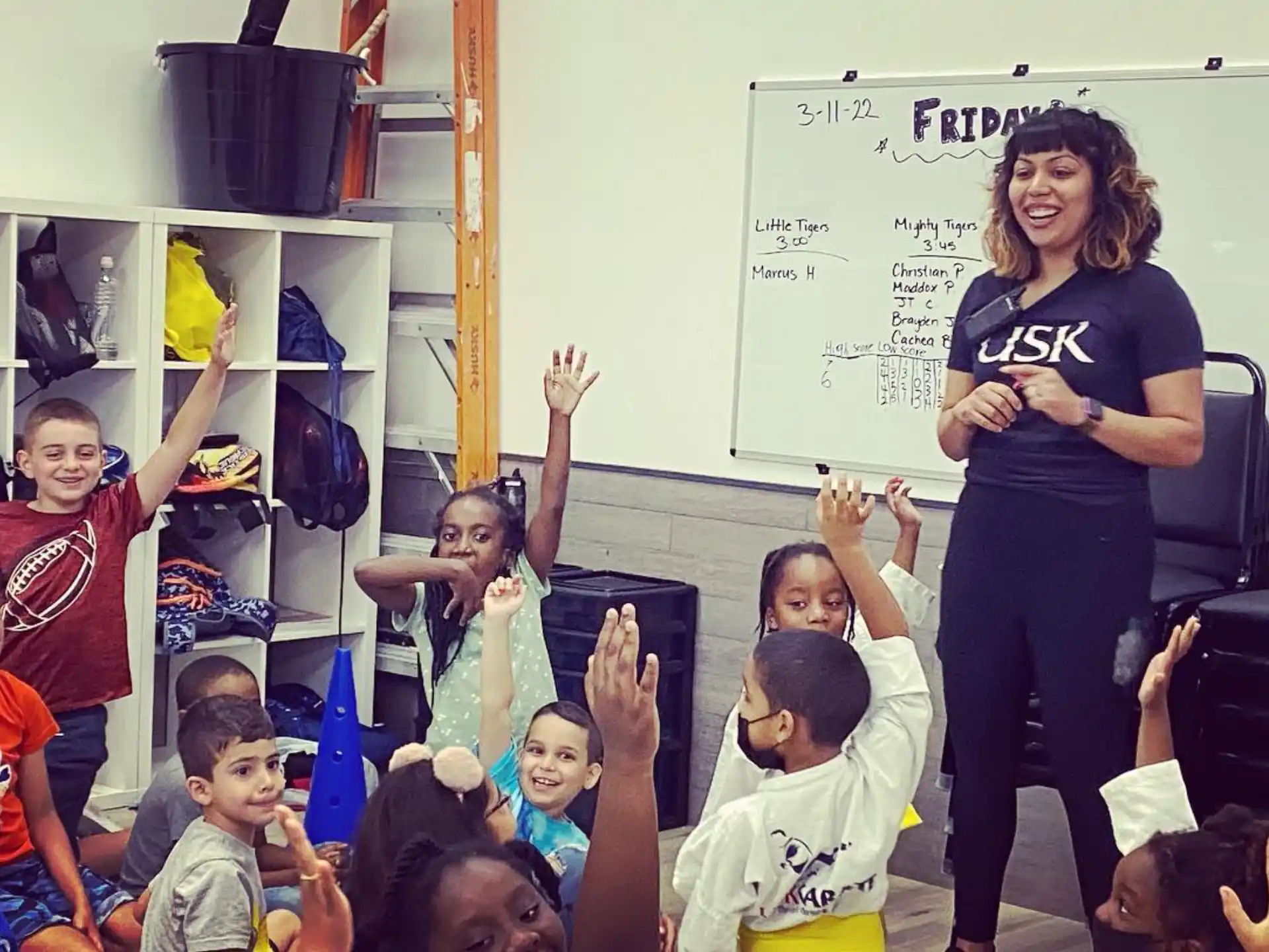 a person standing in front of a group of children raising their hands