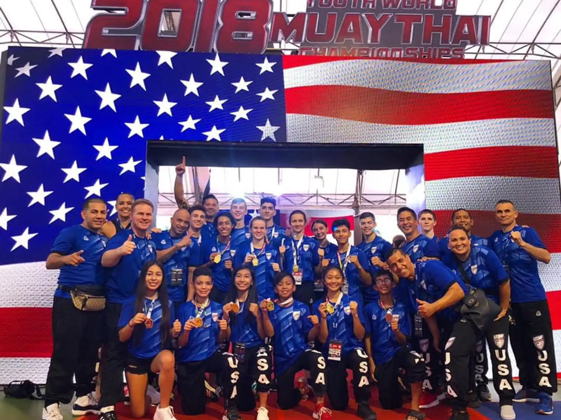 a group of people in blue uniforms posing for a photo in front of a flag