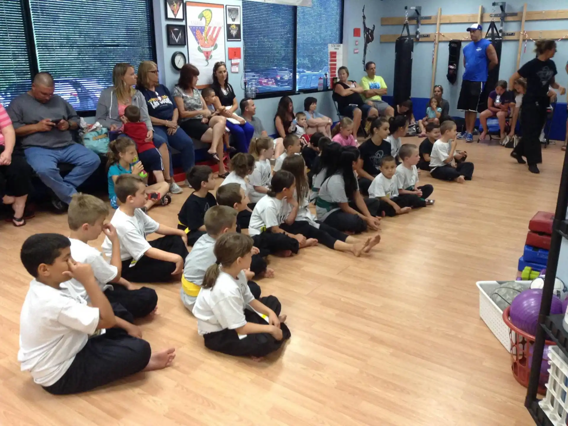 a group of children sitting on the floor in front of a person standing