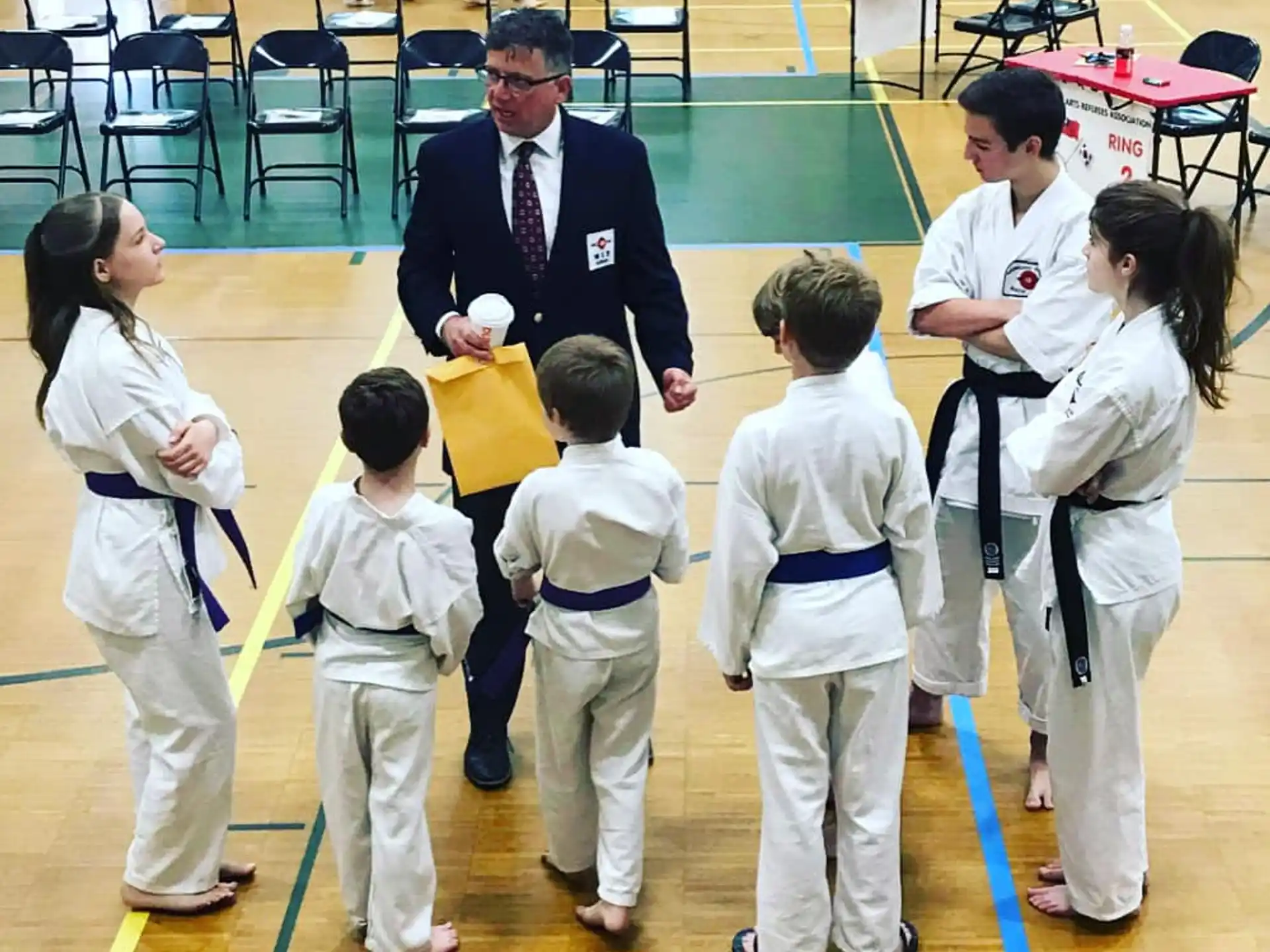 a person standing in front of a group of kids in karate uniforms