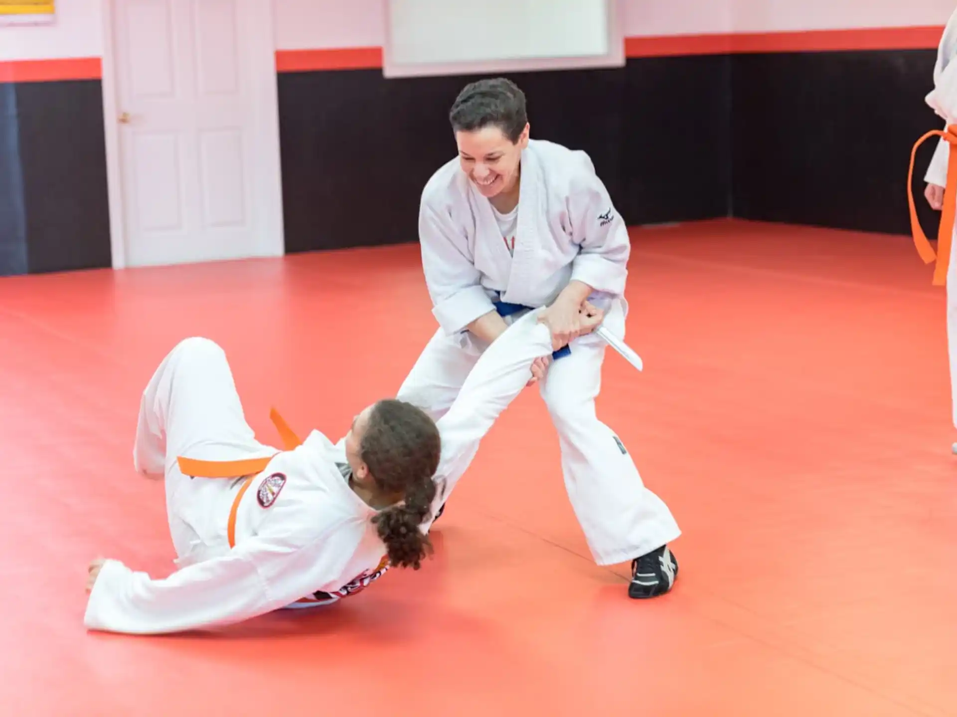a man in white karate uniform kicking another man in a white uniform
