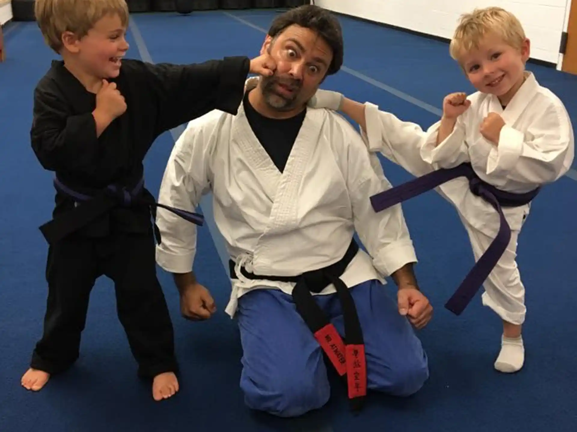 a person and two boys in karate uniforms