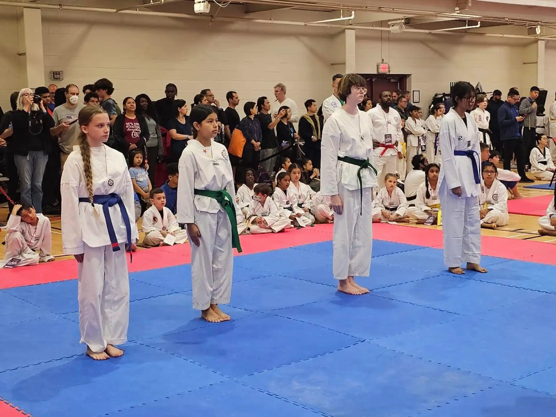 a group of people in white robes standing on a red mat in front of a crowd