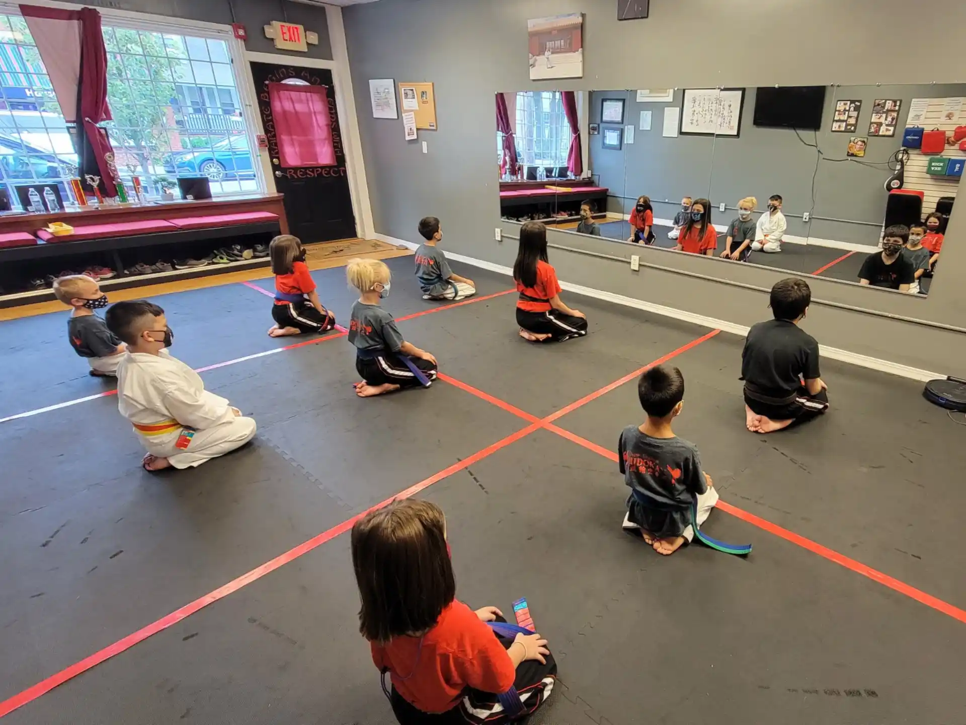 a group of children sitting on the floor in a room with a screen