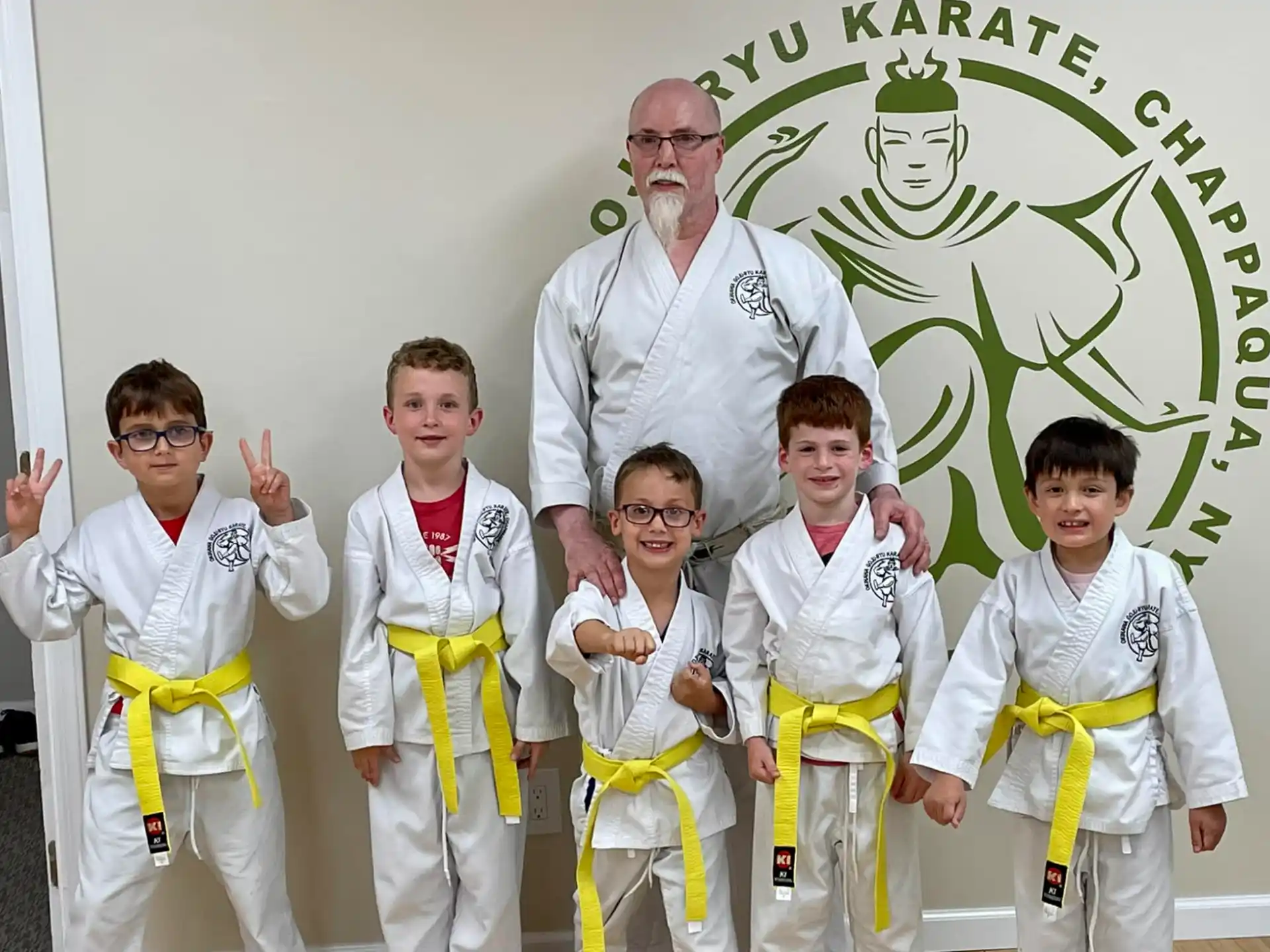 a person standing with a group of kids in karate uniforms