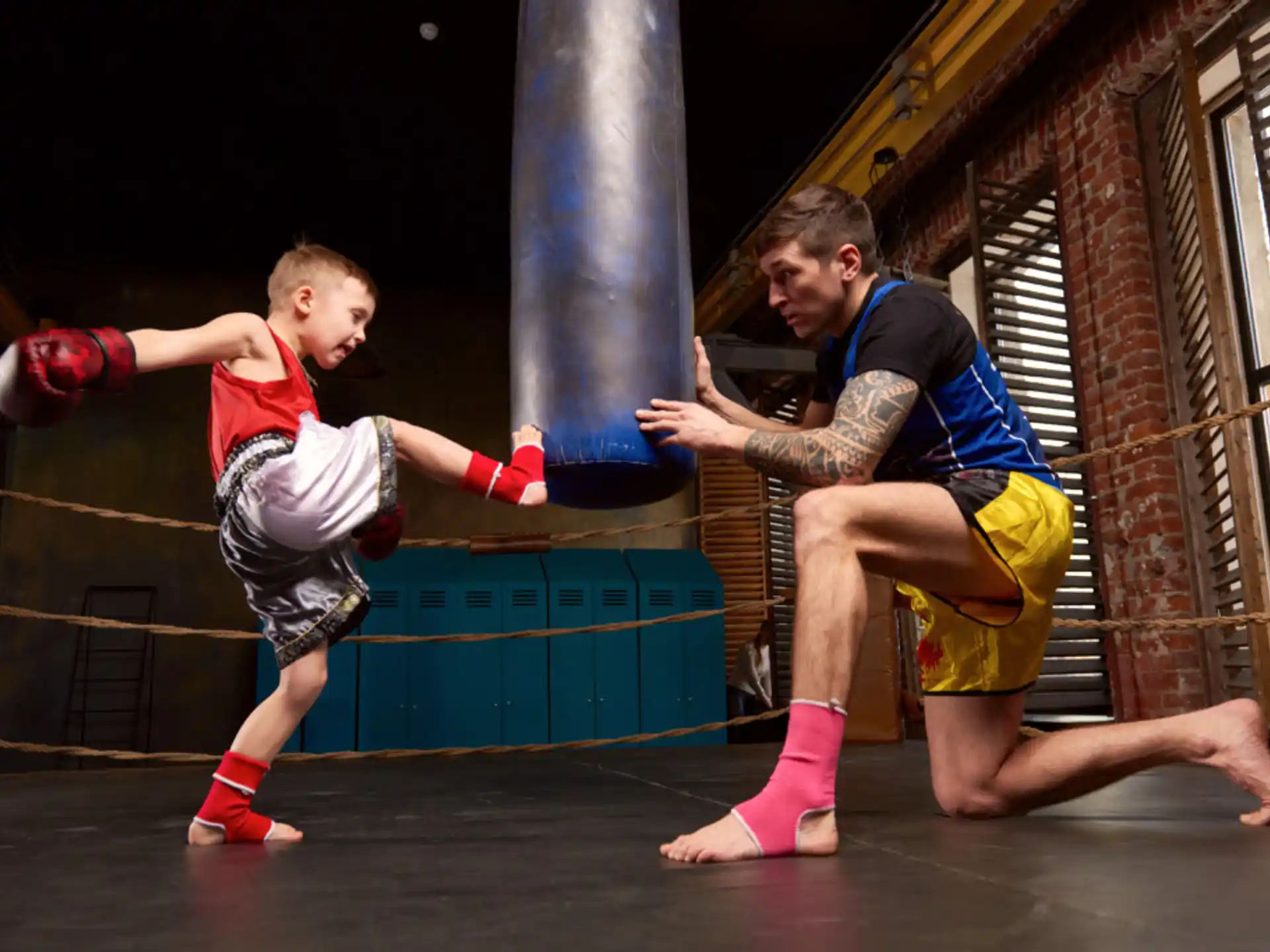 a person and a boy in boxing gloves in a gym