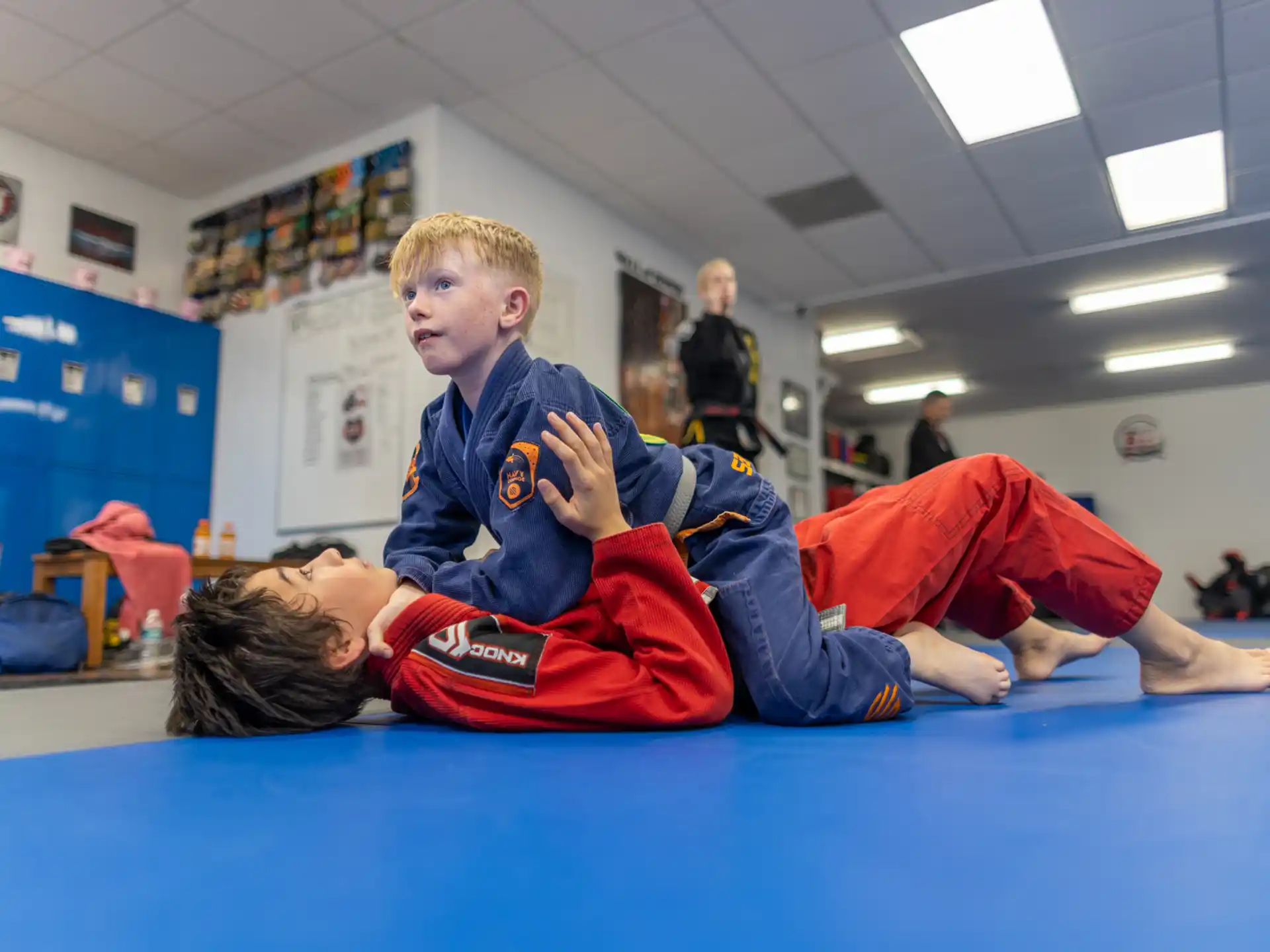 a boy and a girl lying on a blue mat in a classroom