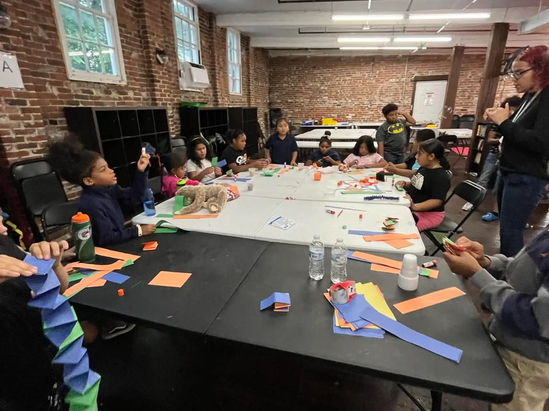 a group of people sitting at a table with colorful paper on it