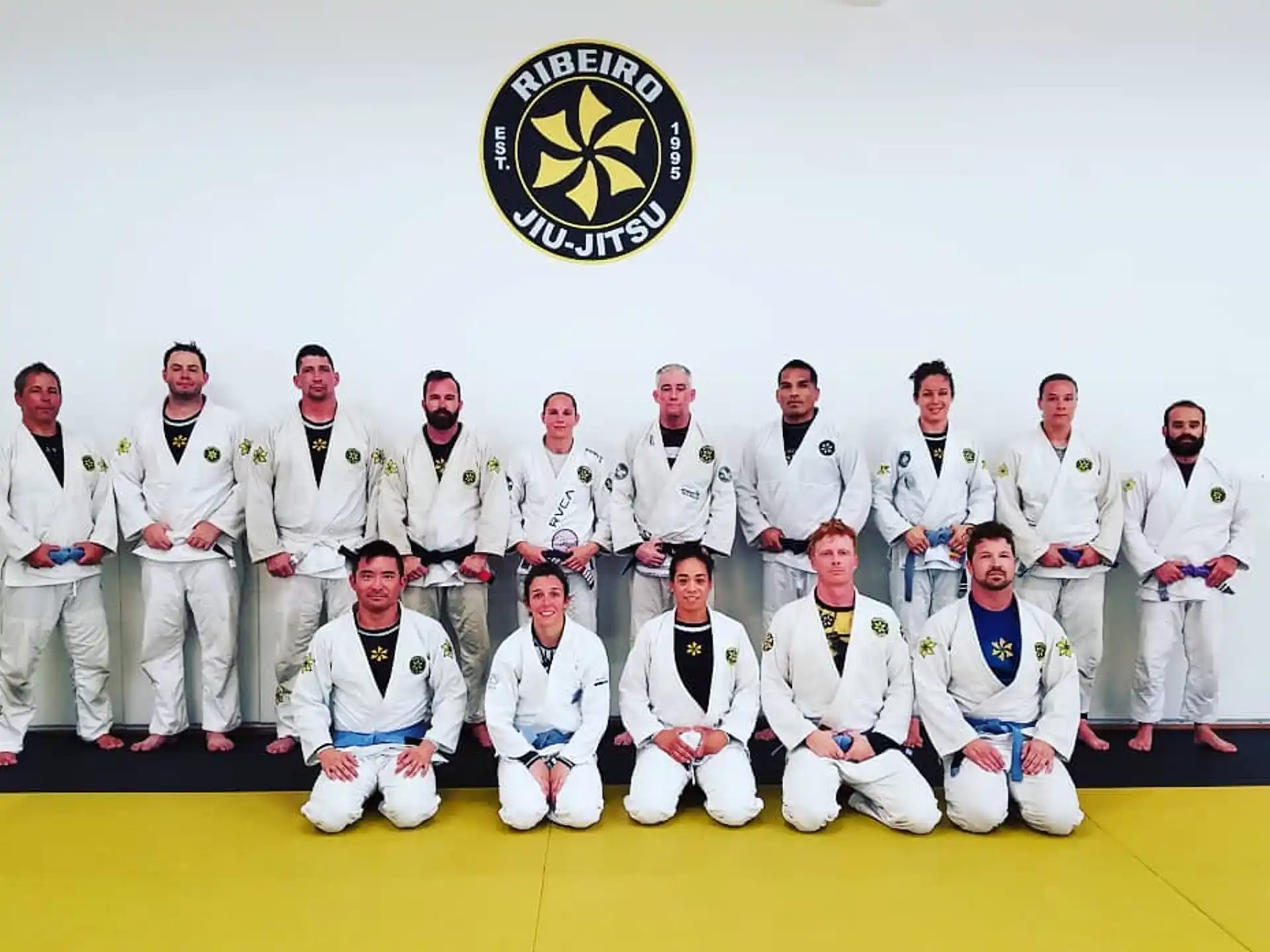 a group of people in white karate uniforms posing for a photo