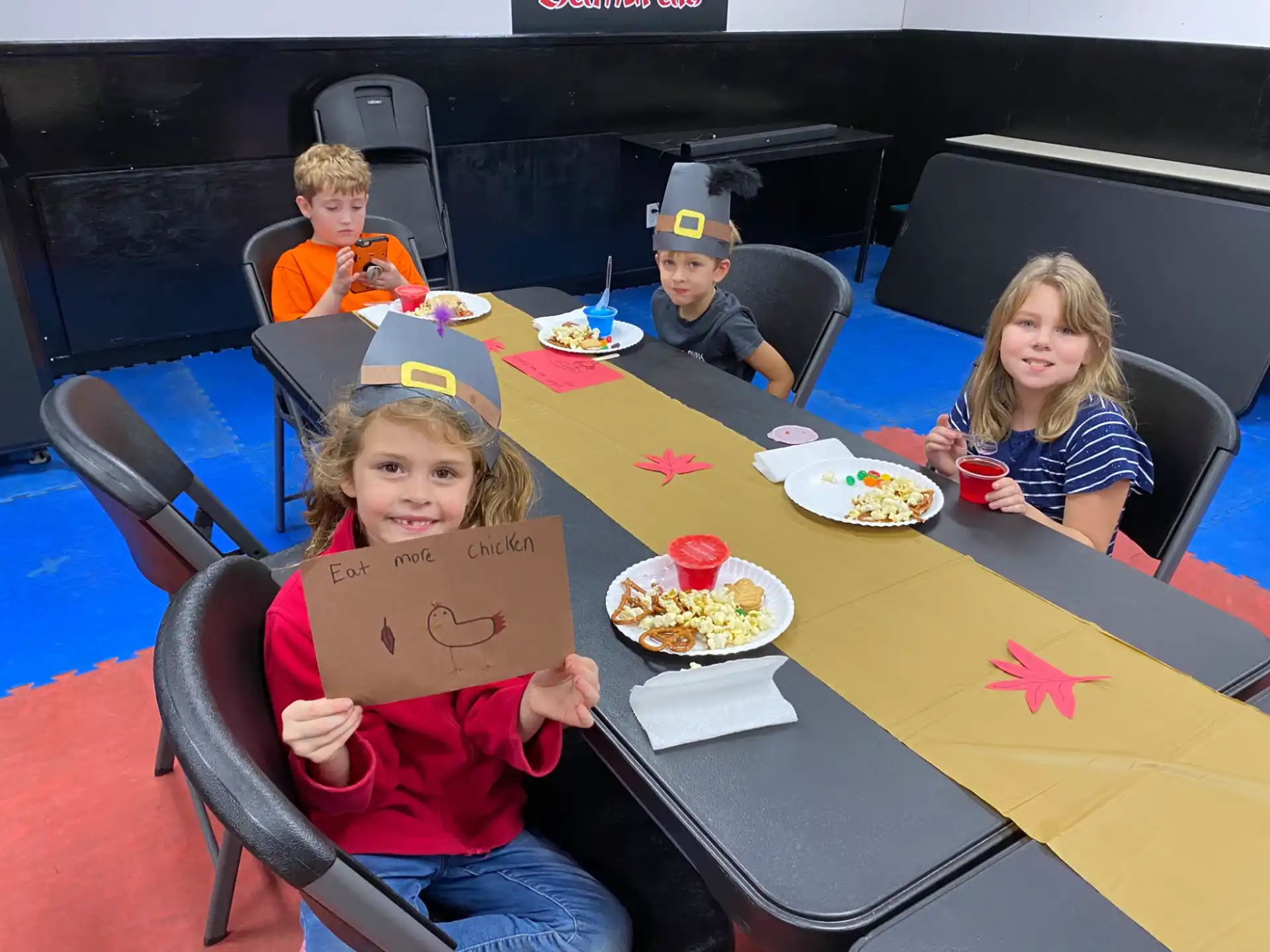 a group of kids sitting at a table with food and drinks