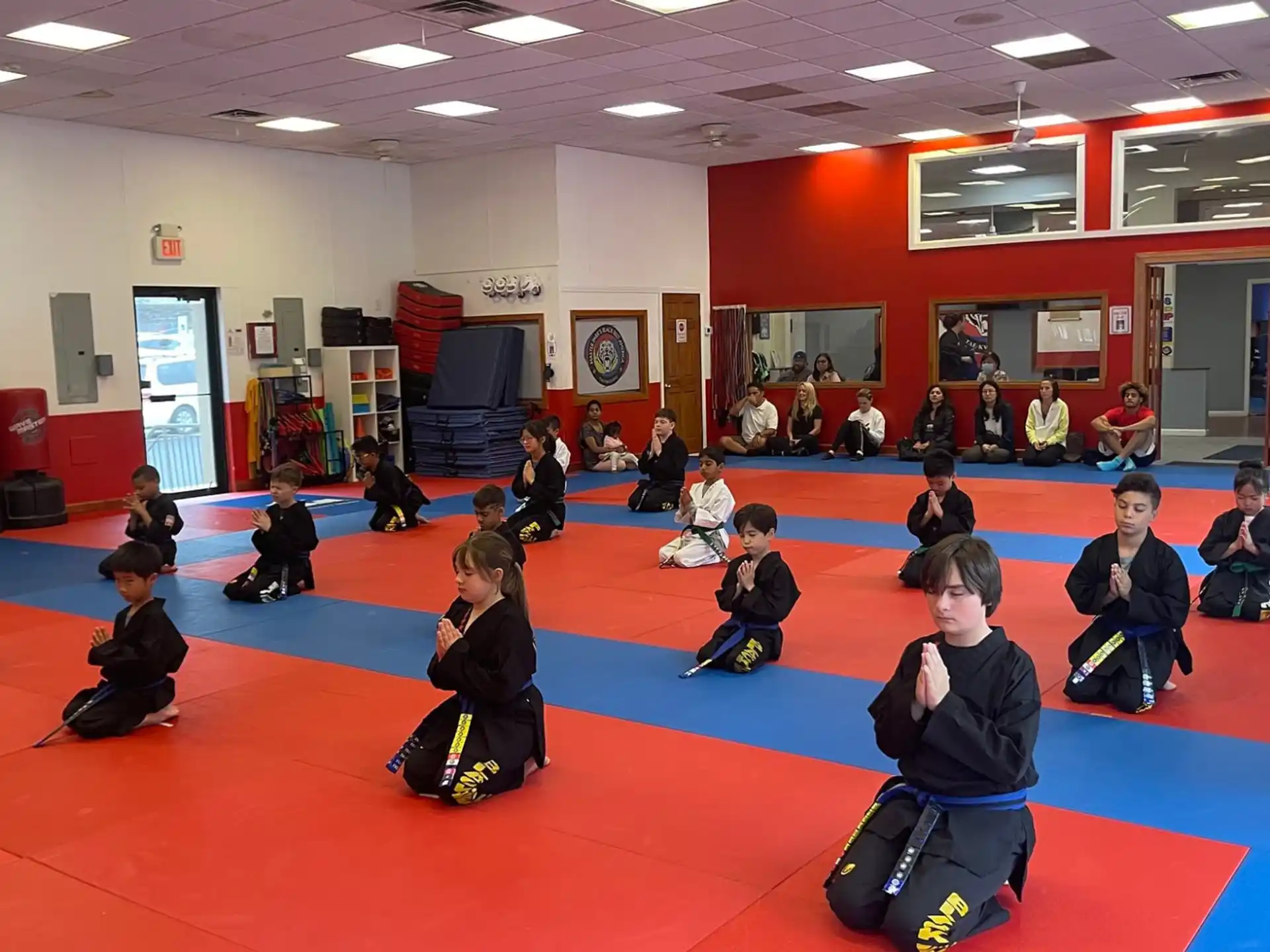 a group of children sitting on a red mat in a room