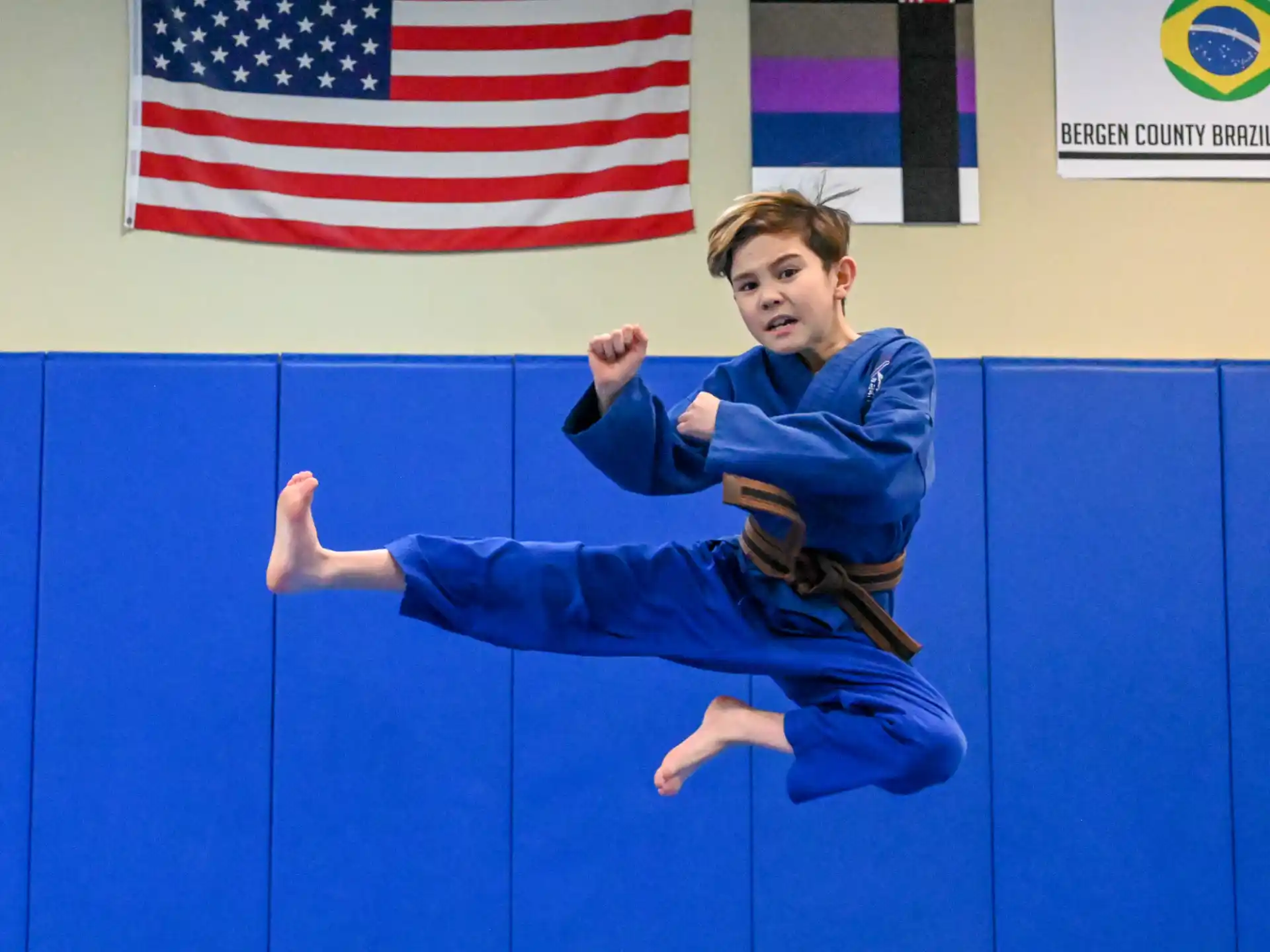 a boy in a blue uniform with a guitar in front of a flag