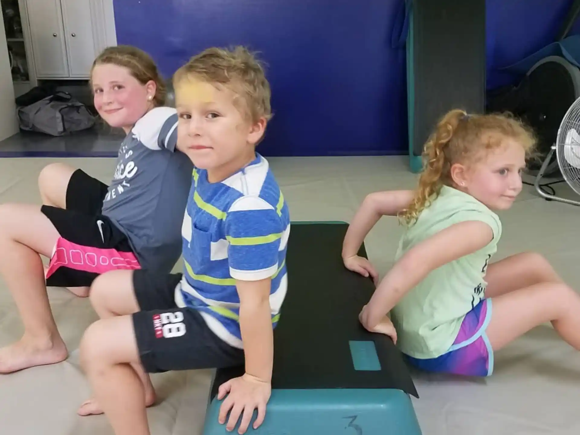 a group of children sitting on a purple mat