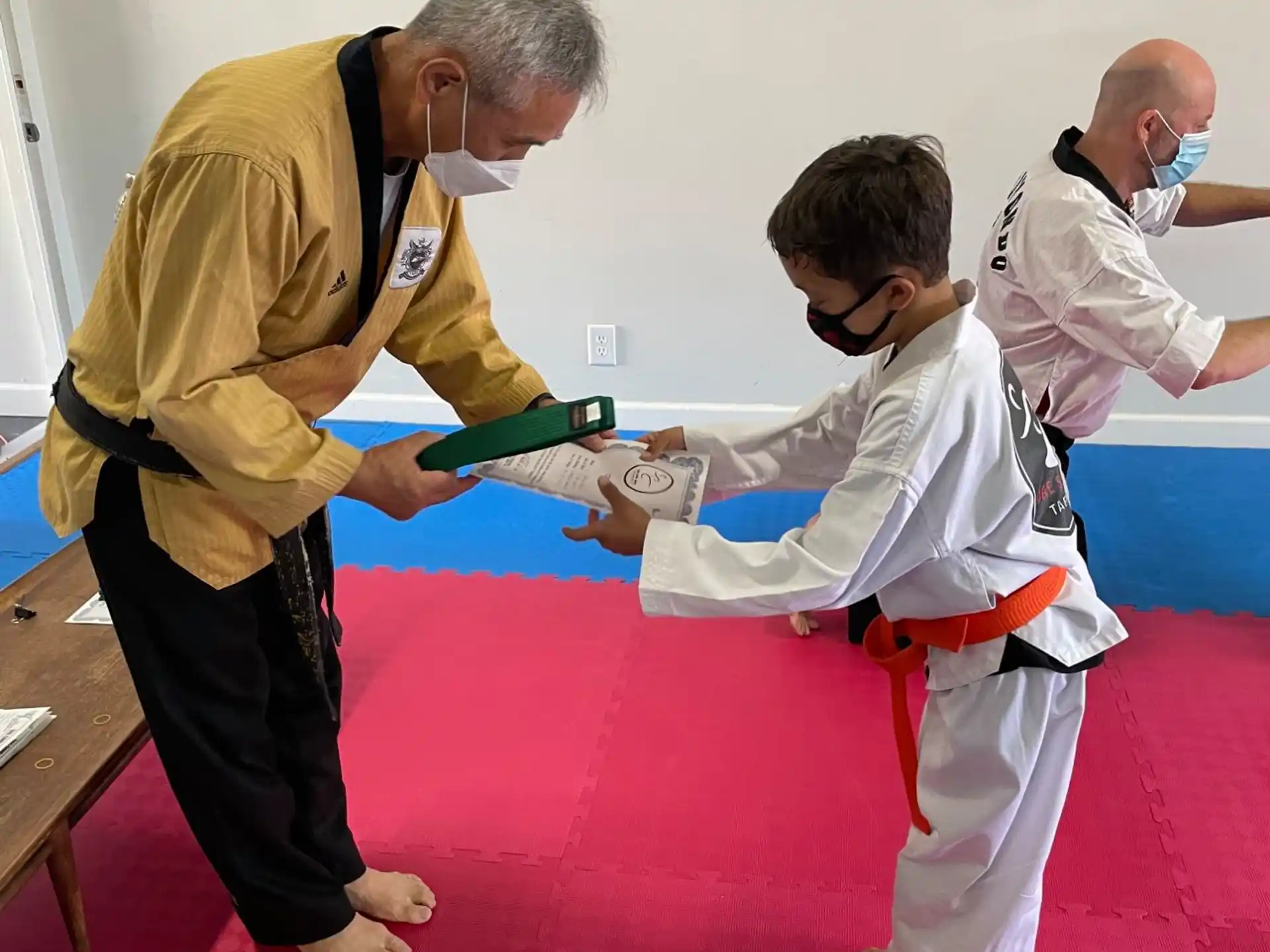 a man in a karate uniform holding a sword and another man in a yellow shirt