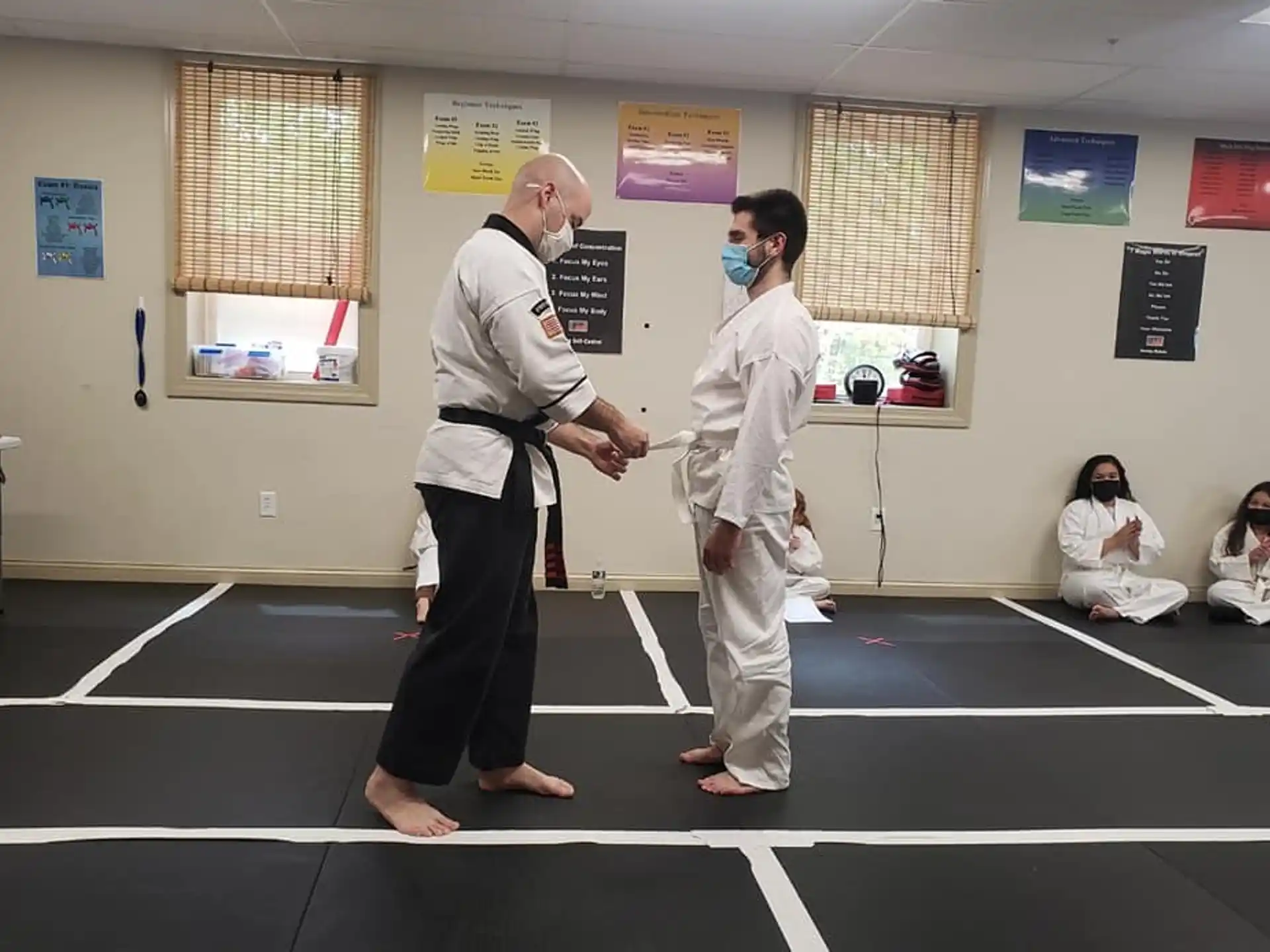 a man and a woman in karate uniforms in a room with other people