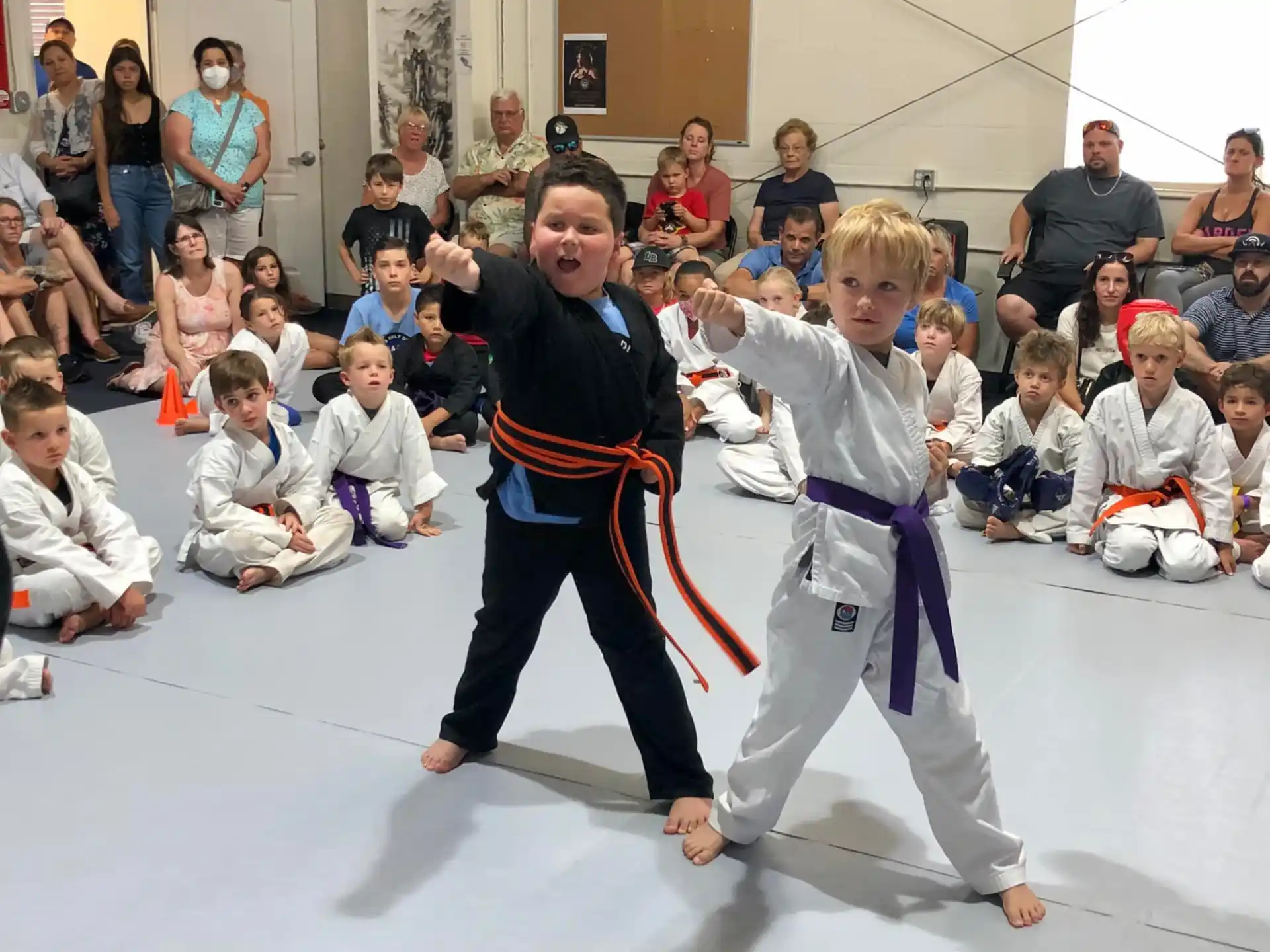 a person and a boy in karate uniforms with a crowd watching