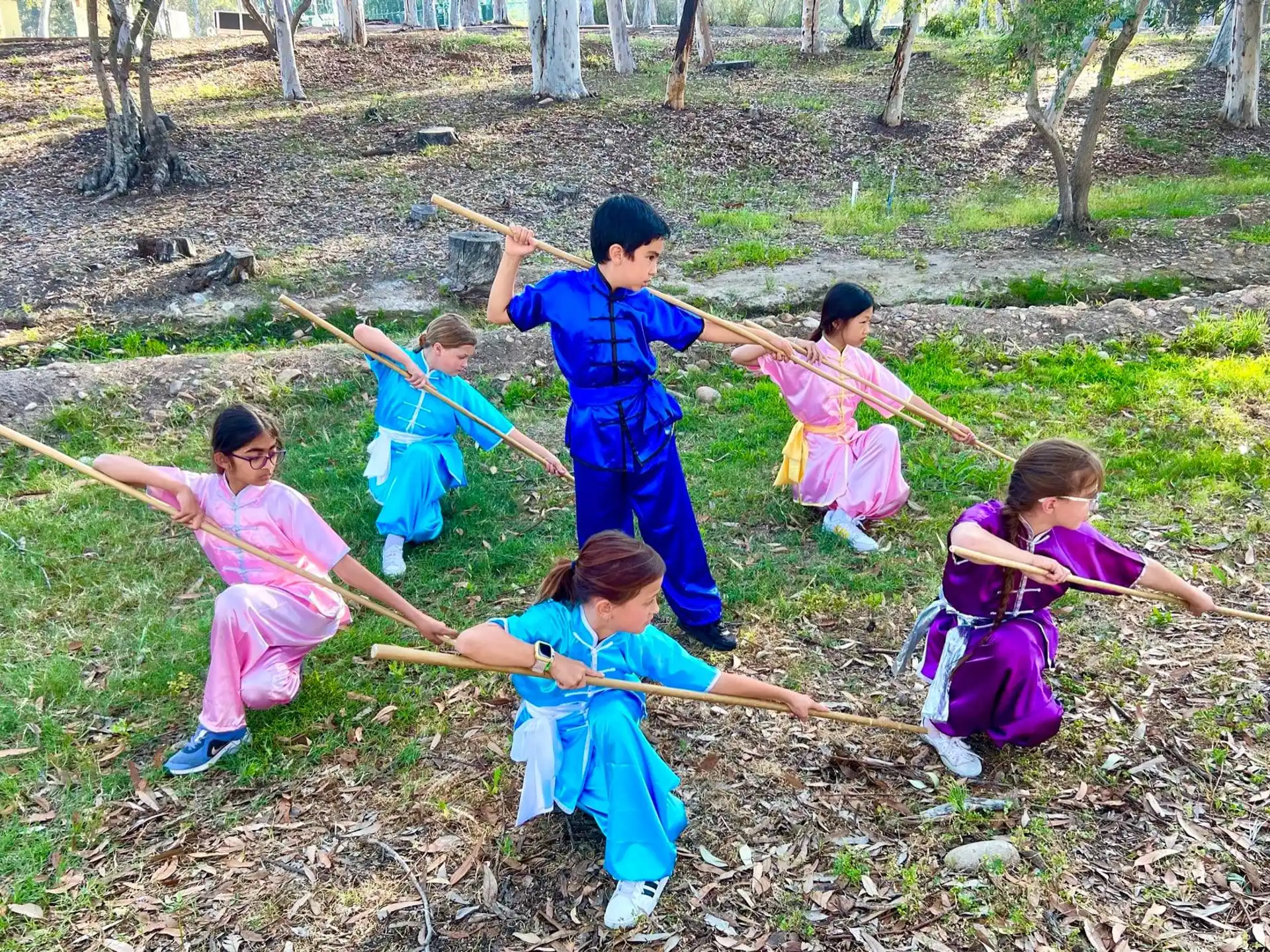 a group of children in blue and pink clothes holding sticks