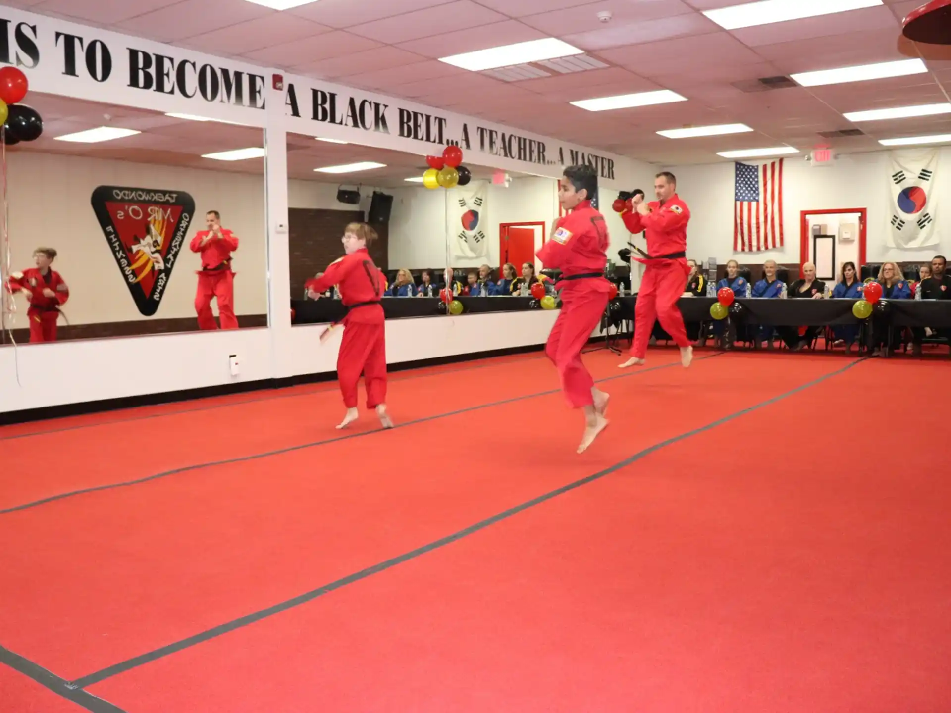 a group of people in red uniforms on a mat in a room with a flag and a red