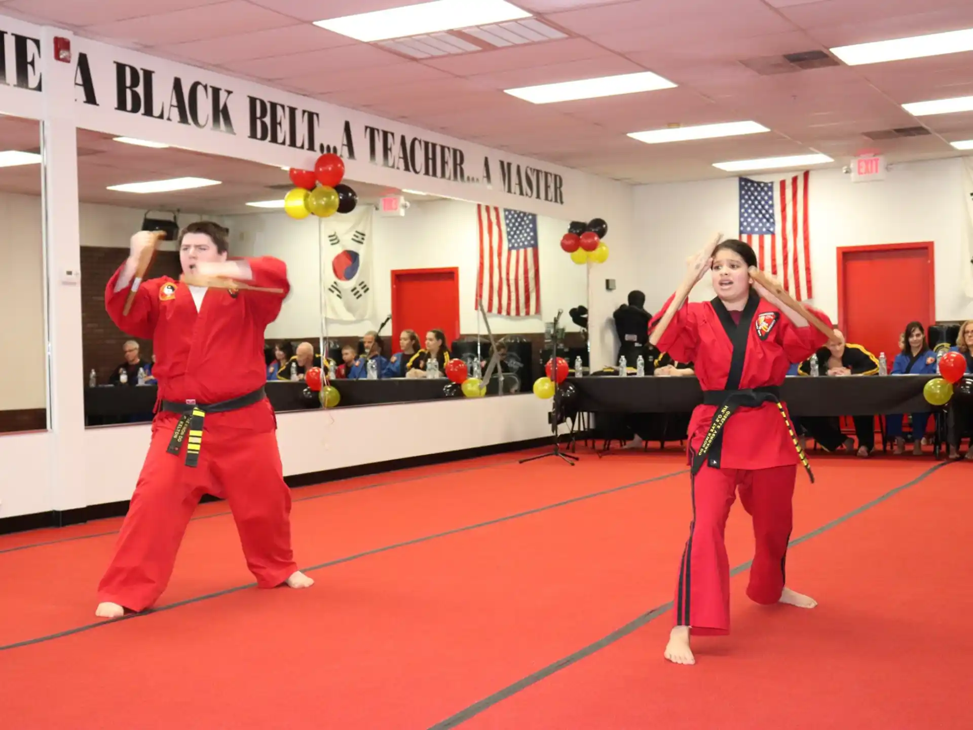 a man and woman in red karate uniforms with a flag and a woman in a red uniform