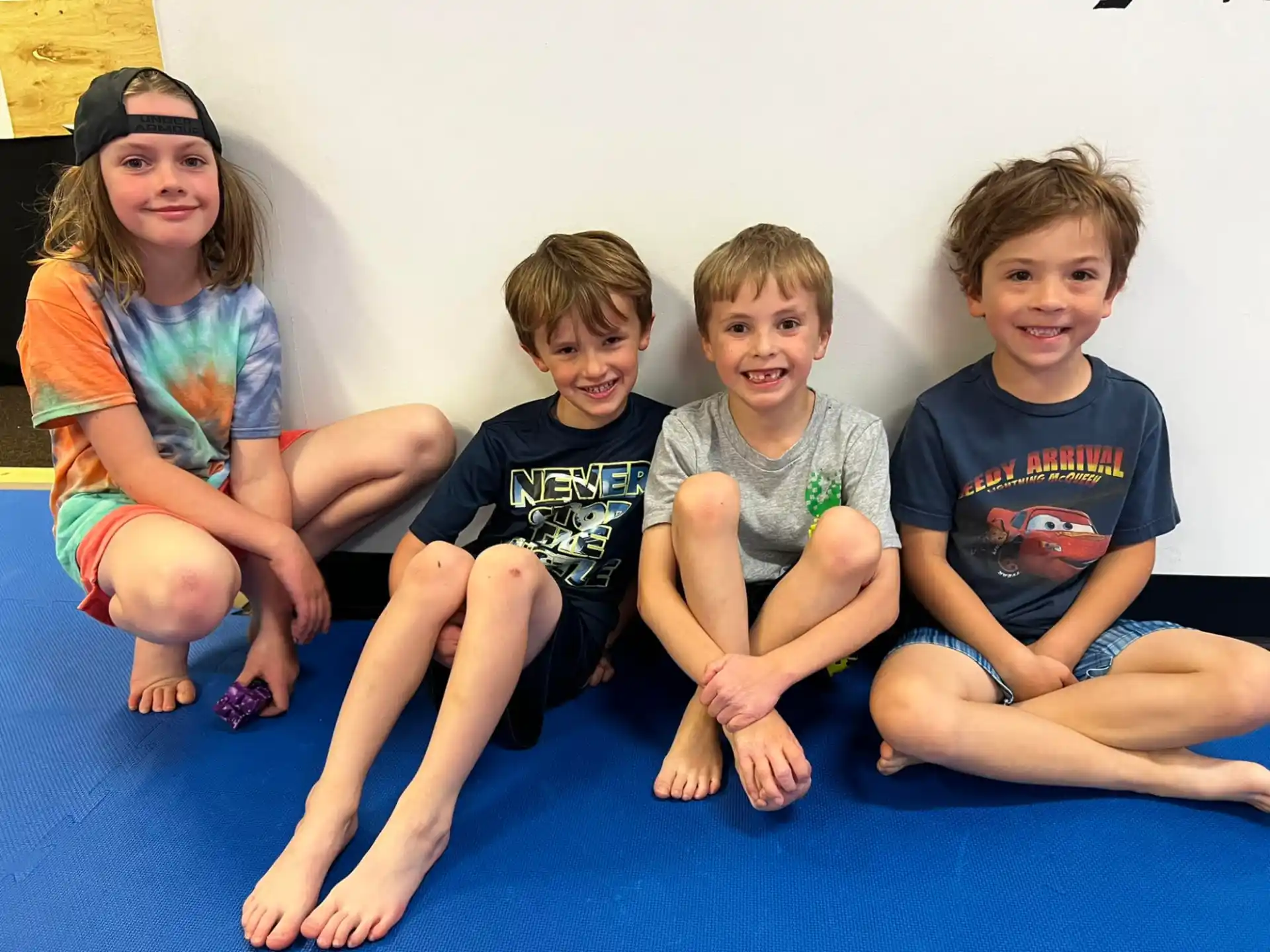 a group of children sitting on a blue mat