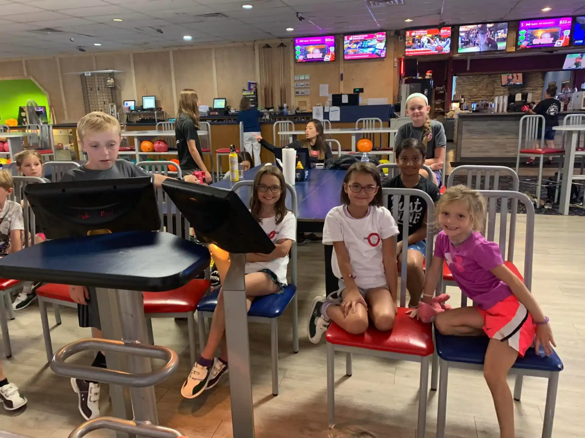 a group of kids sitting at a table with a laptop