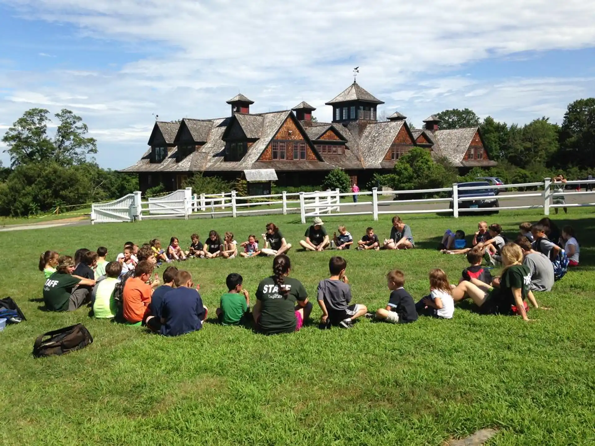 a group of people sitting on the grass in front of a house