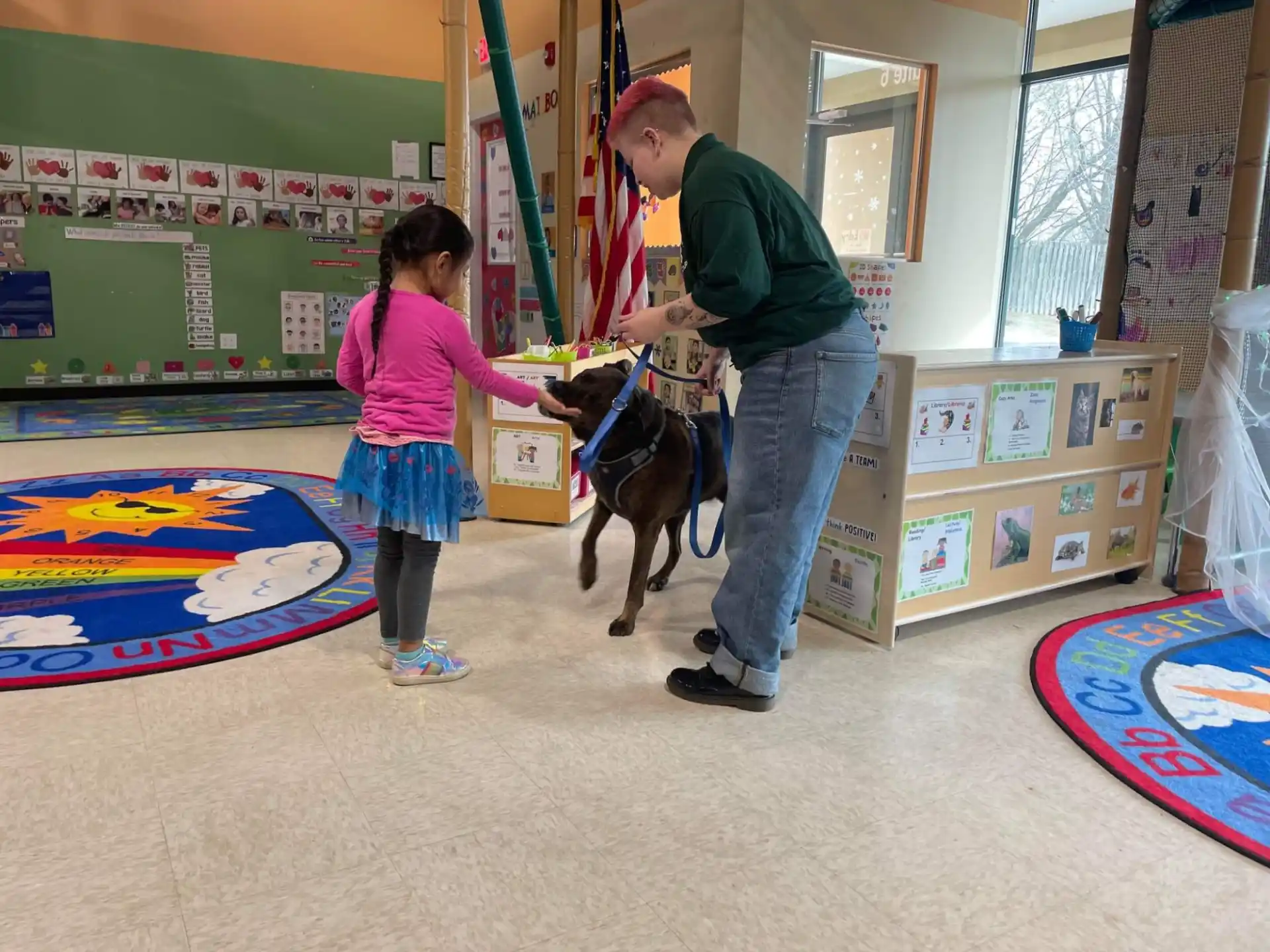 a person and a girl petting a dog in a room